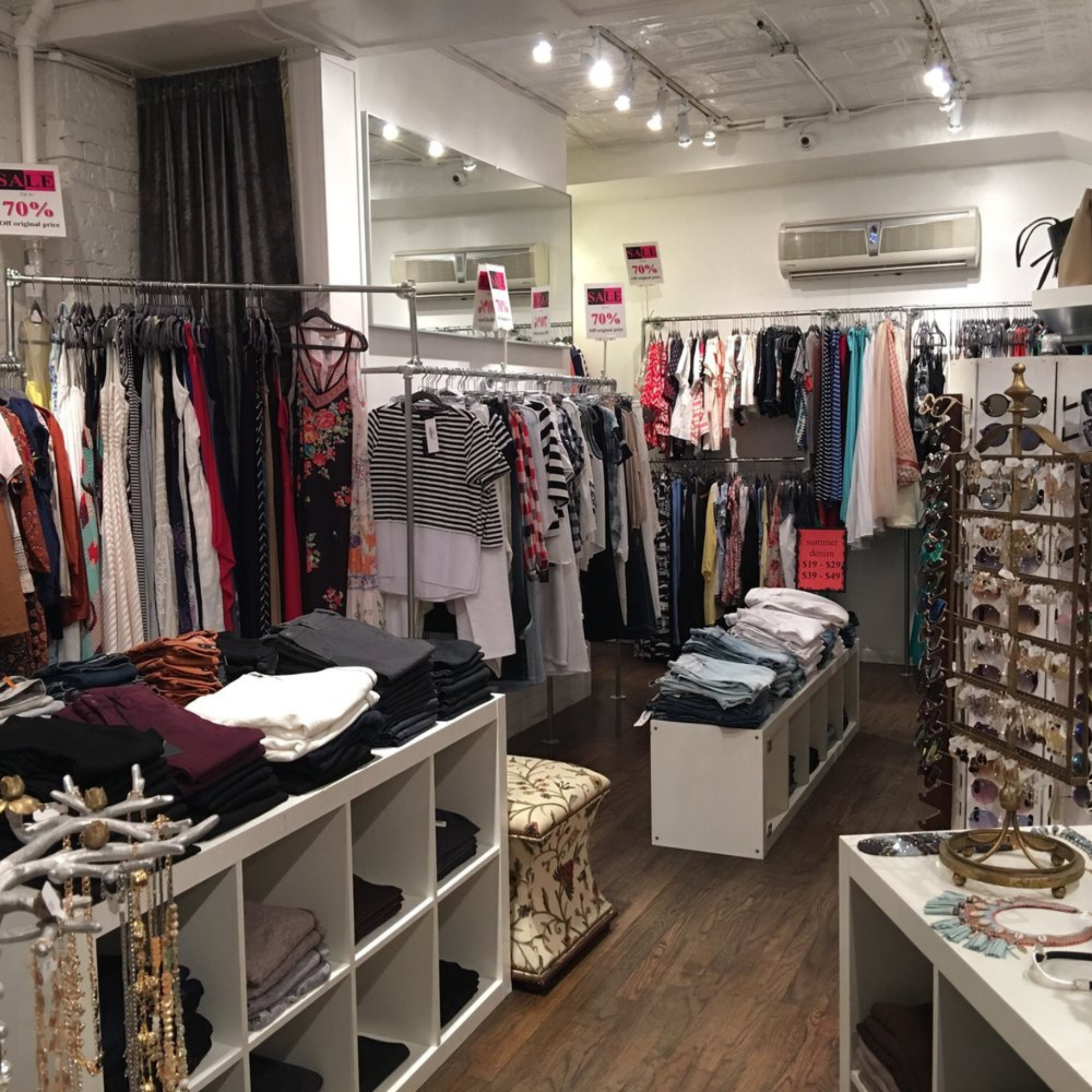 Clothing boutique with organized racks, folded apparel, and sale signs