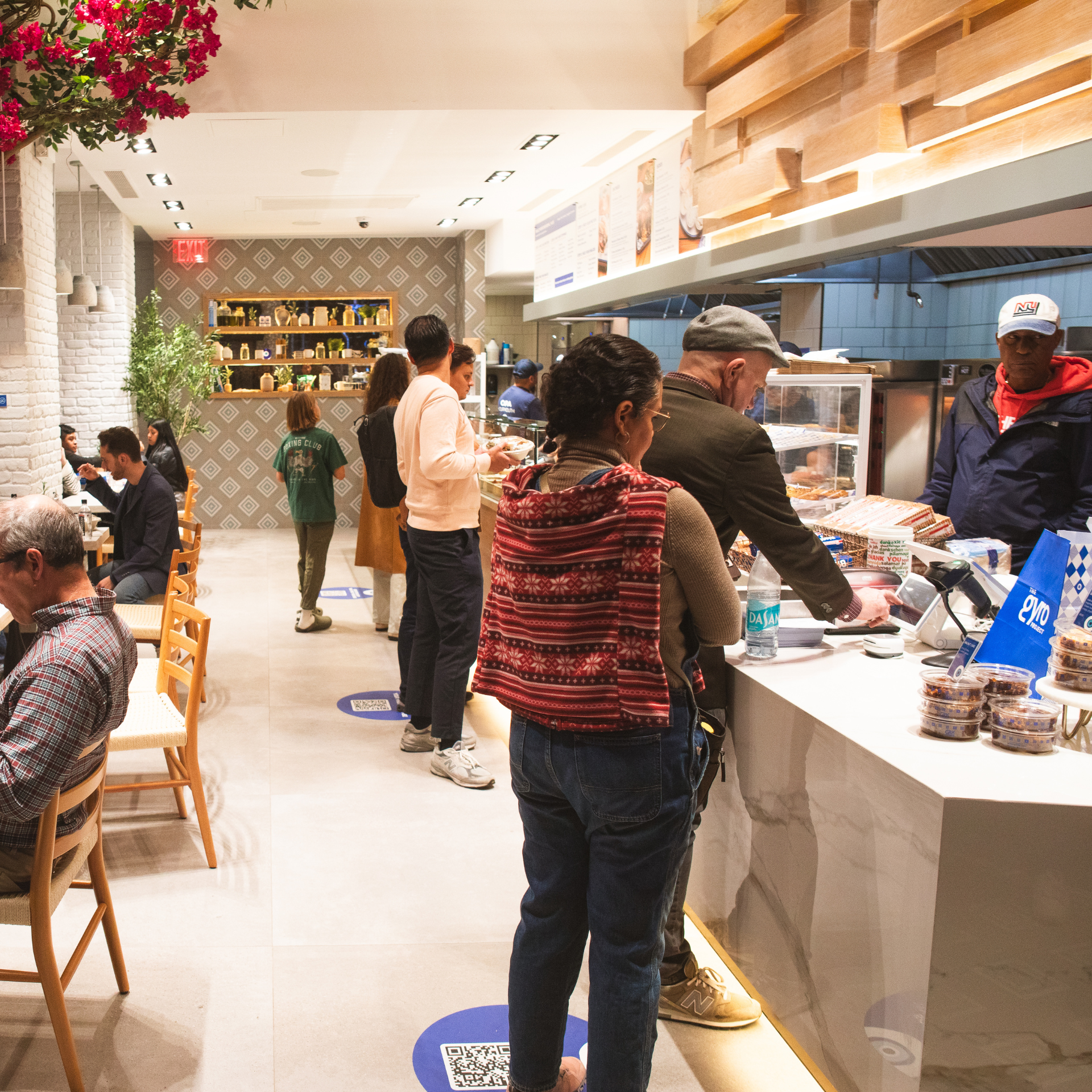 Modern dining spot featuring wooden tables, floral ceiling decor, and social distancing floor markers