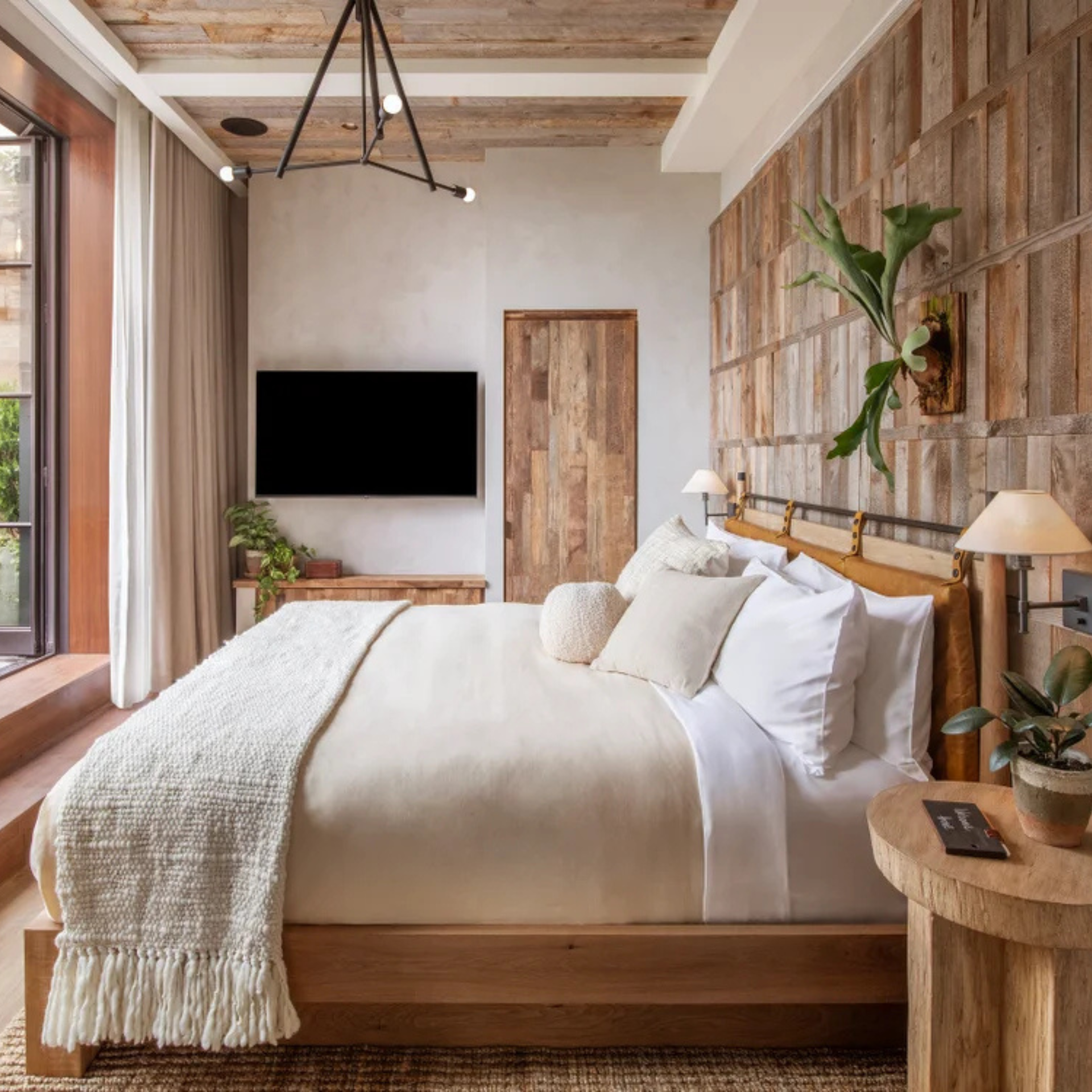 Cozy bedroom with wood-paneled walls, white and beige bedding, and rustic-modern decor