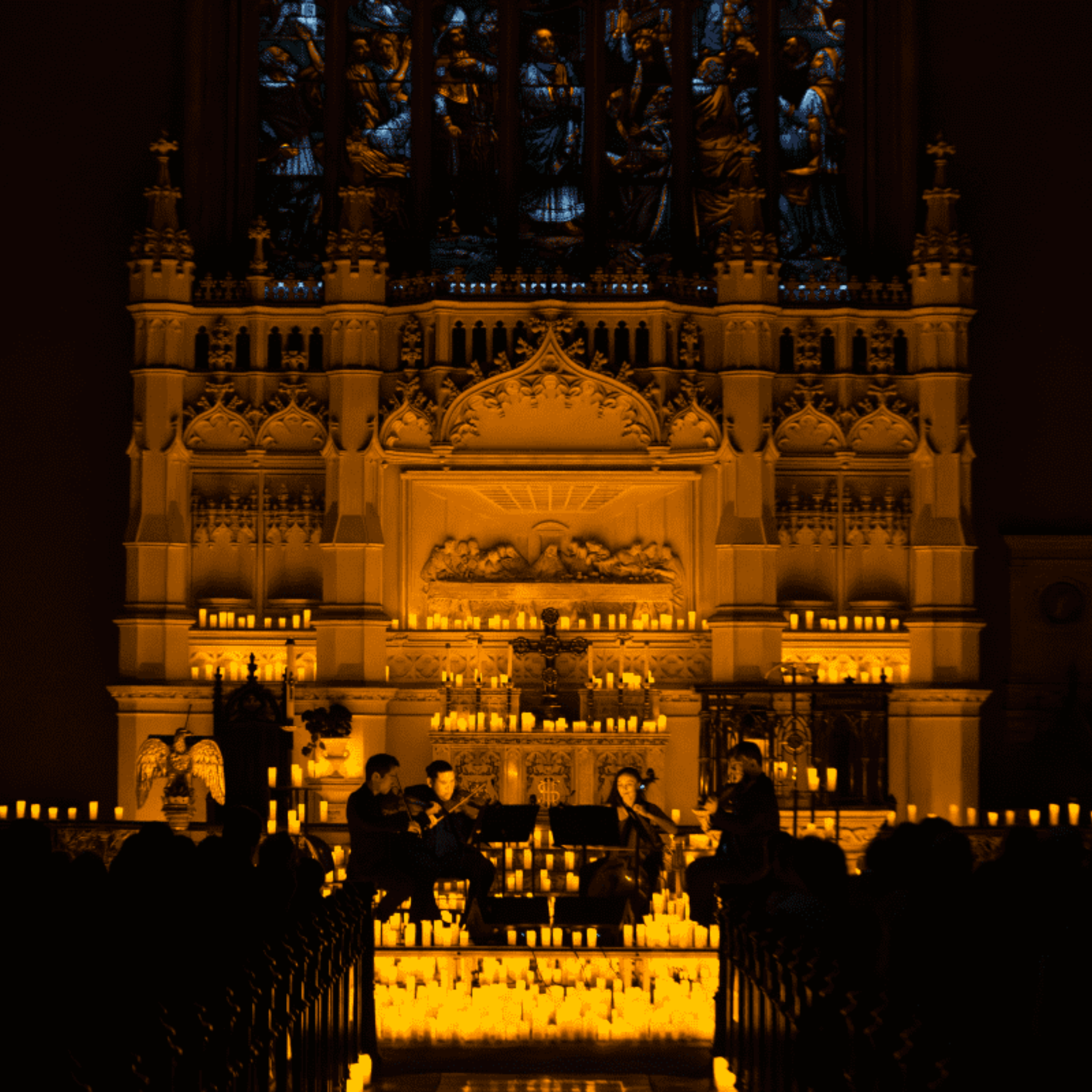 String quartet performing by candlelight in a historic church with ornate altar and stained glass