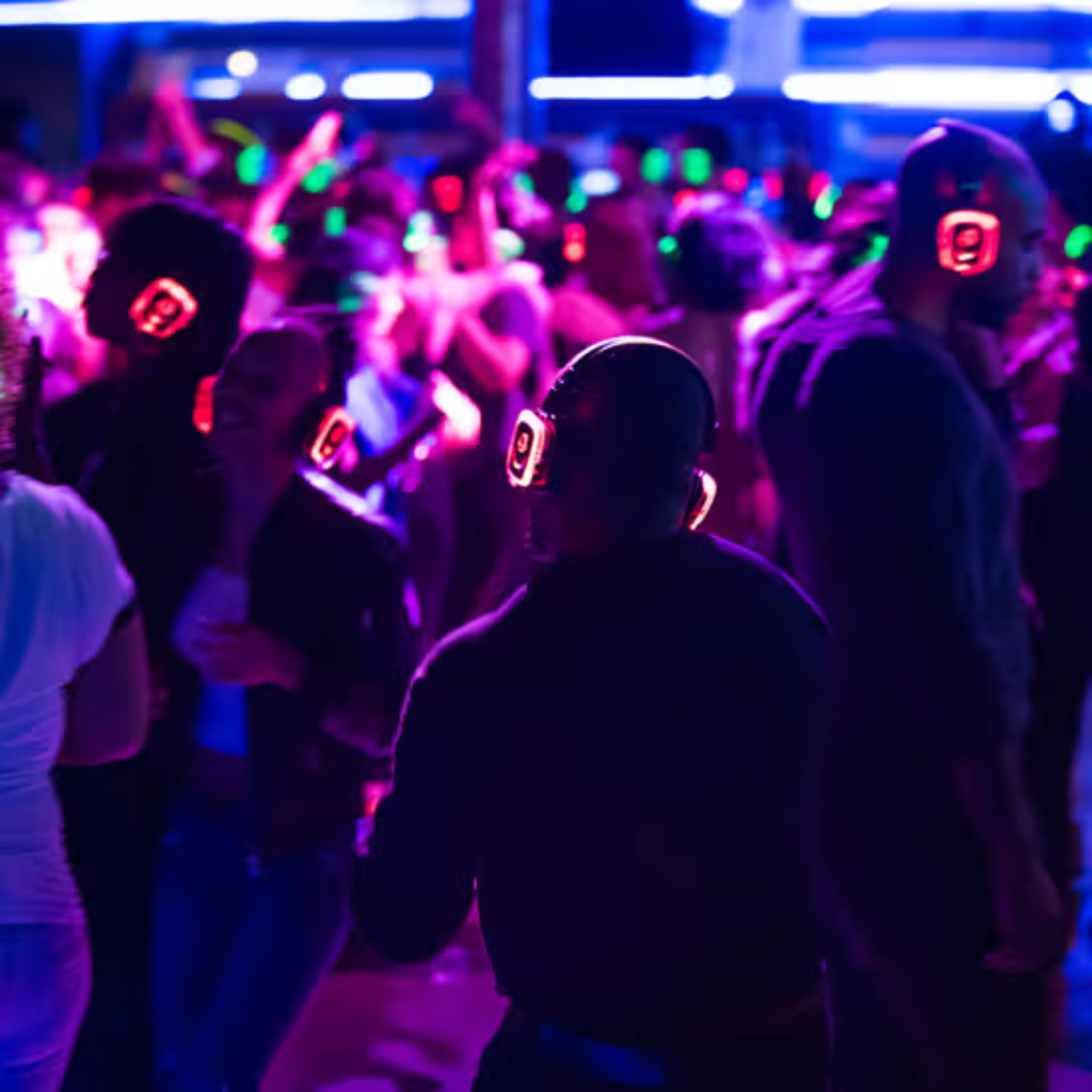 People dancing at a silent disco with glowing headphones and colorful lights in a dark party setting