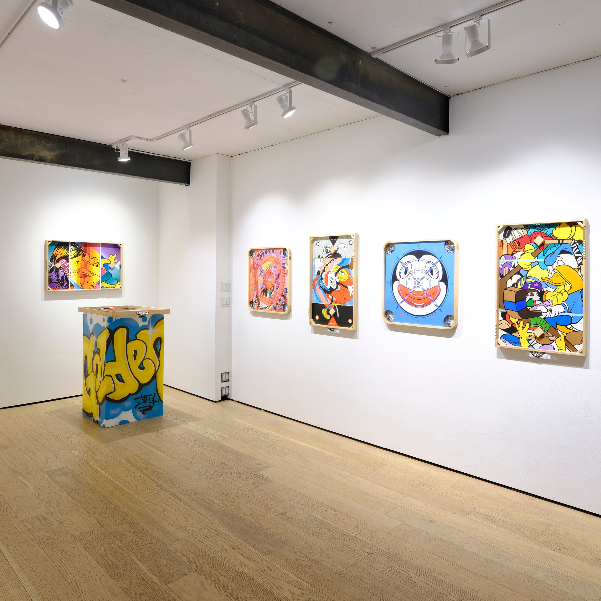 Contemporary art gallery with colorful cartoon-style pop art and graffiti pedestal on display