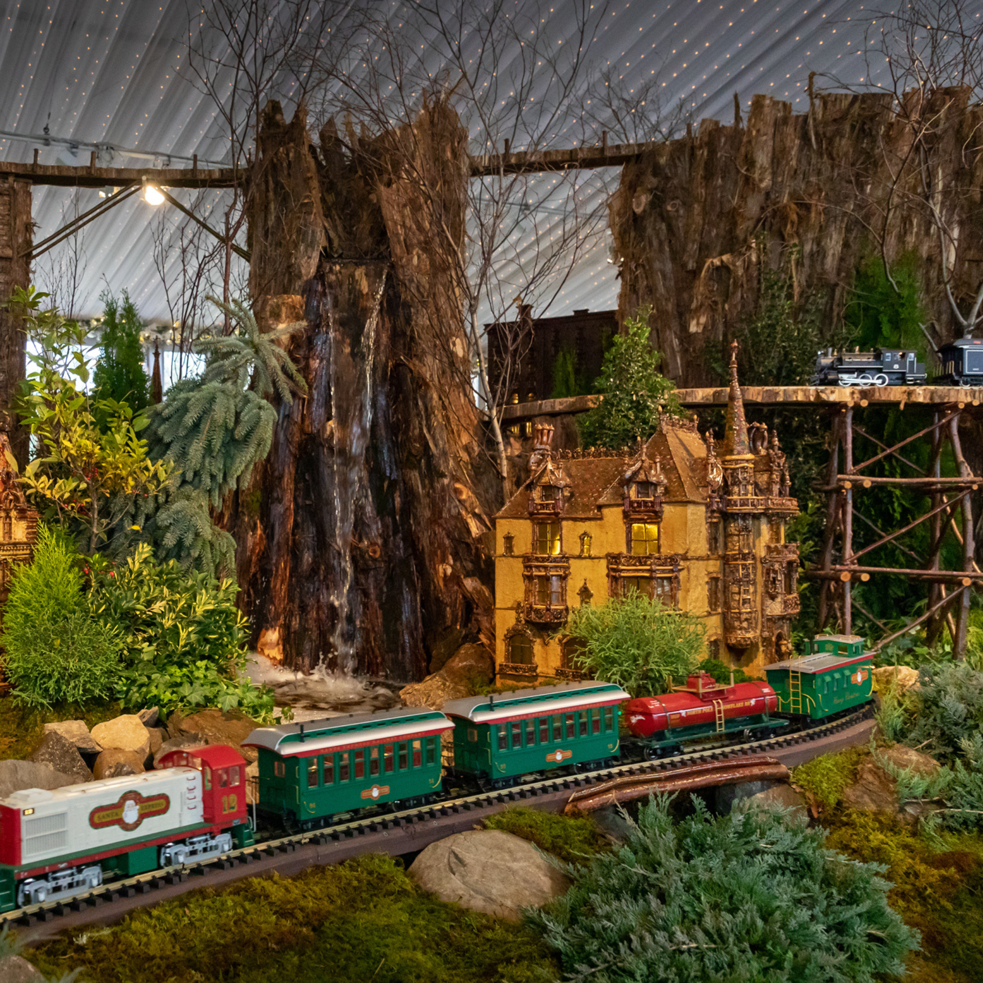 NYC Things To Do this Week: Detailed model train scene with castle, waterfall, and forested tracks under twinkling lights
