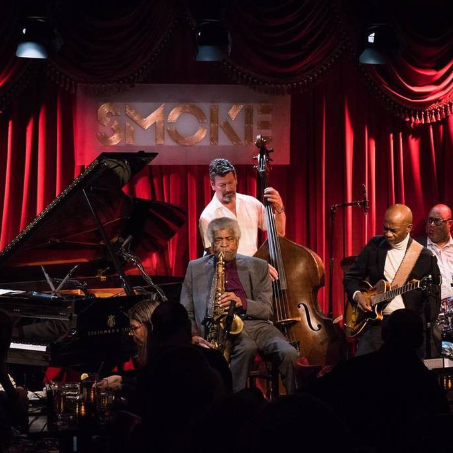 Live jazz band performing at Smoke with red curtains and dramatic lighting