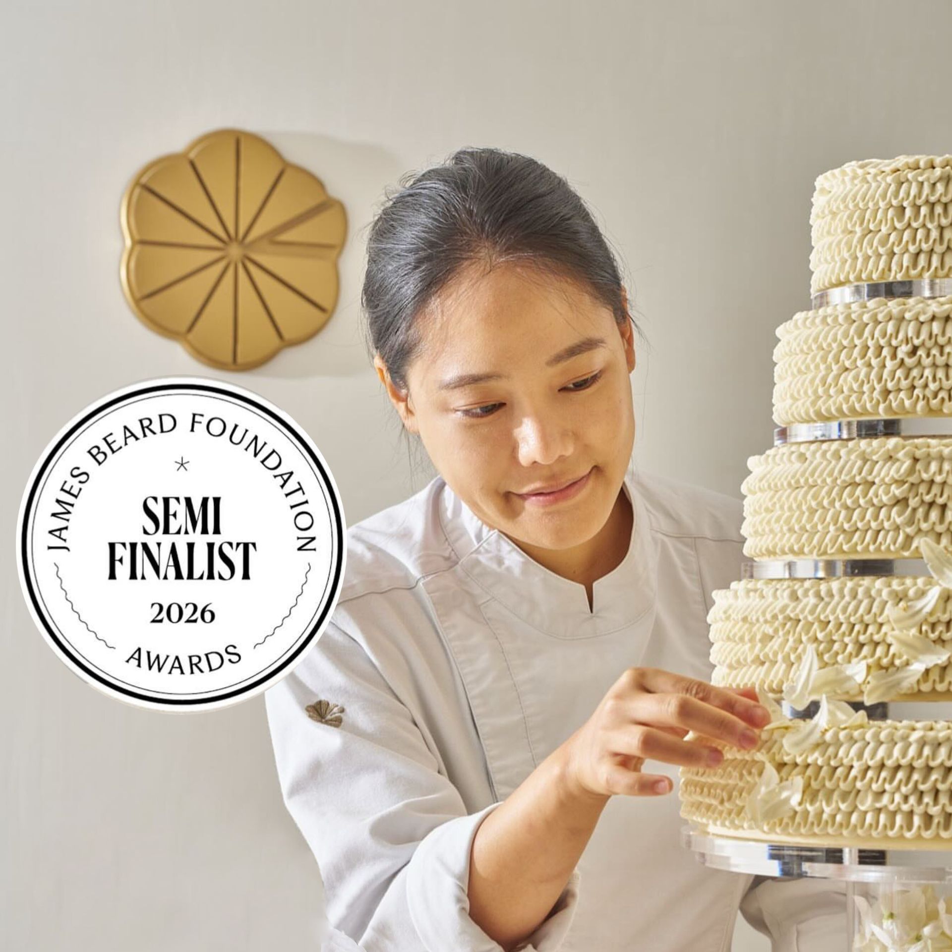 Pastry chef in white uniform decorating tiered cake, recognized as 2026 James Beard Awards semifinalist