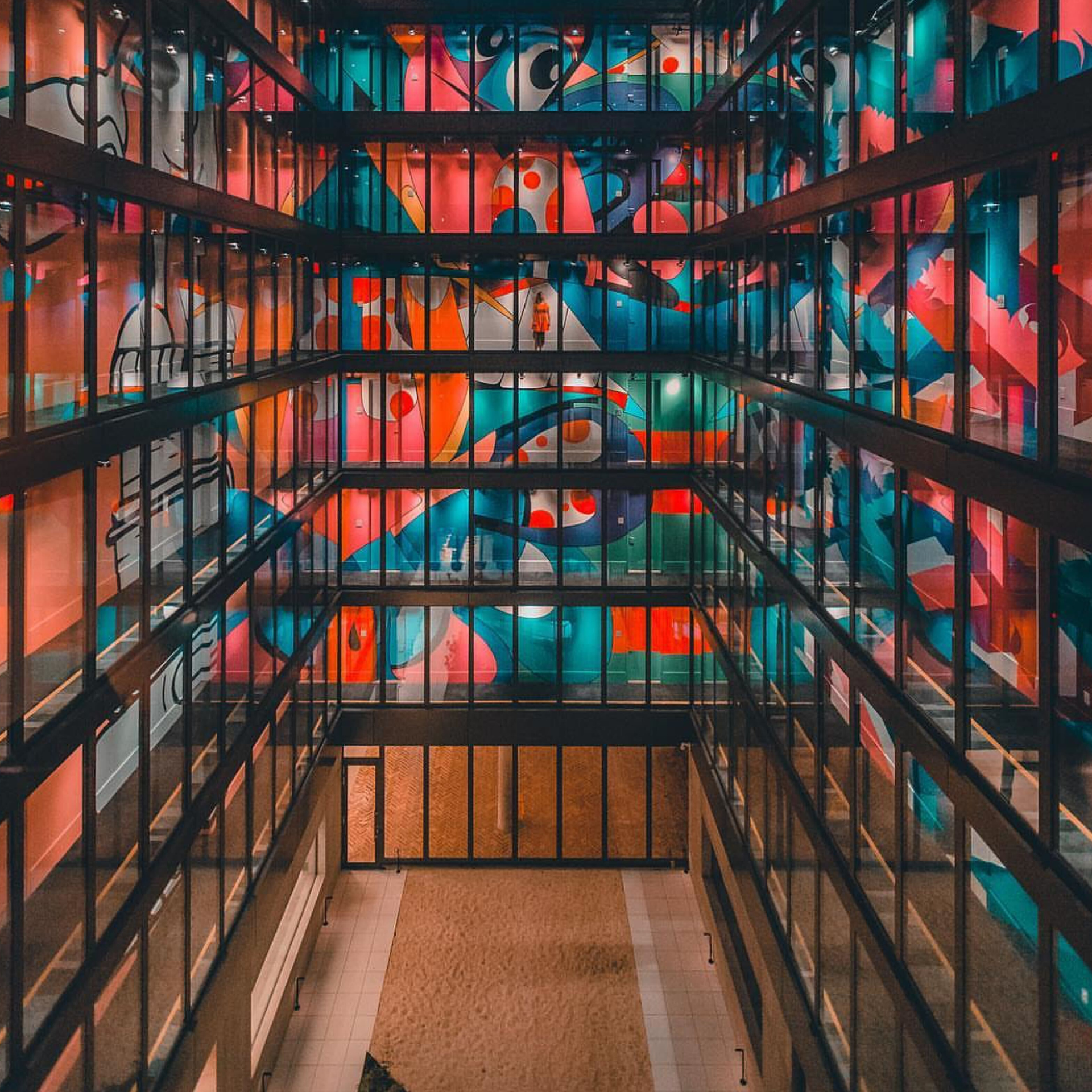 Modern building atrium with vibrant multi-story abstract mural in bold colors