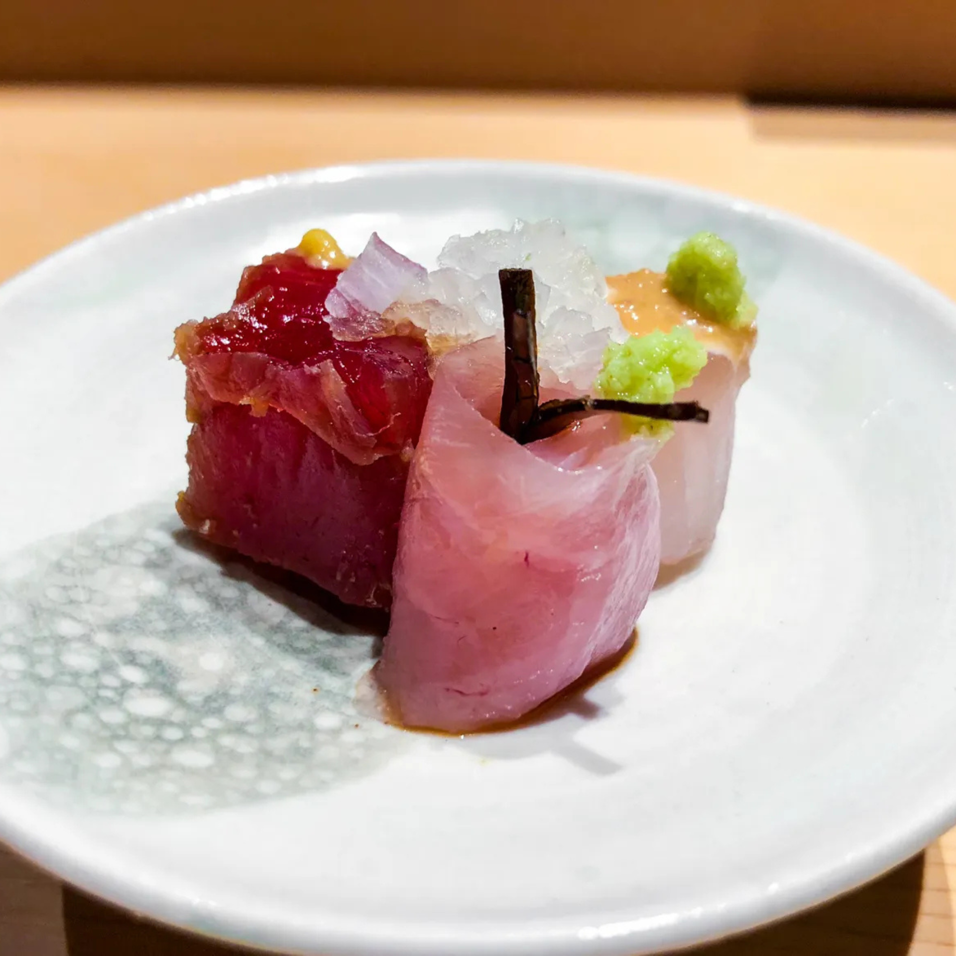 Elegant sashimi platter with tuna, yellowtail, and snapper, garnished with wasabi and daikon on a ceramic plate