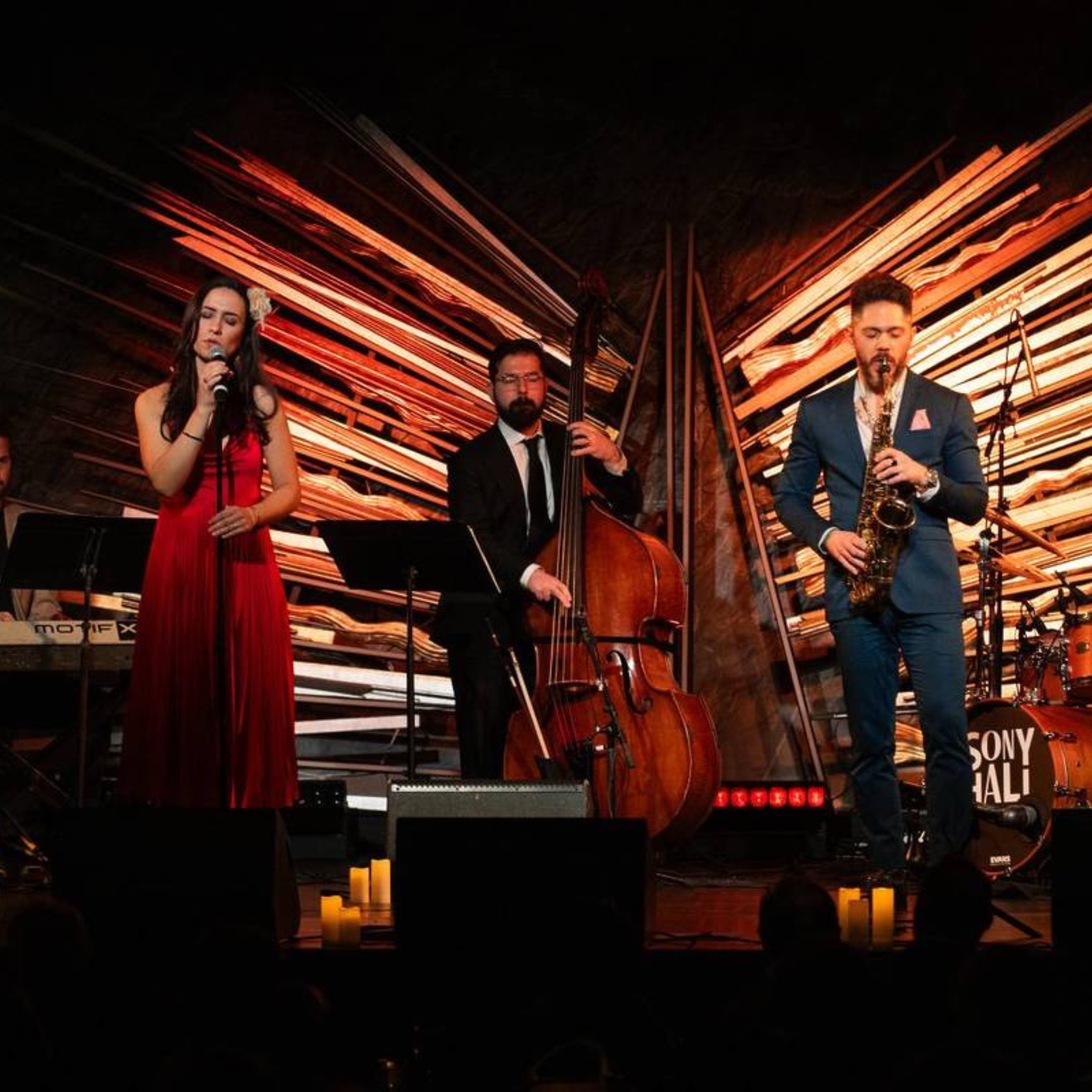 Live jazz band performing on stage at Sony Hall, featuring a vocalist in red, saxophonist, bassist, and keyboard player under warm lighting