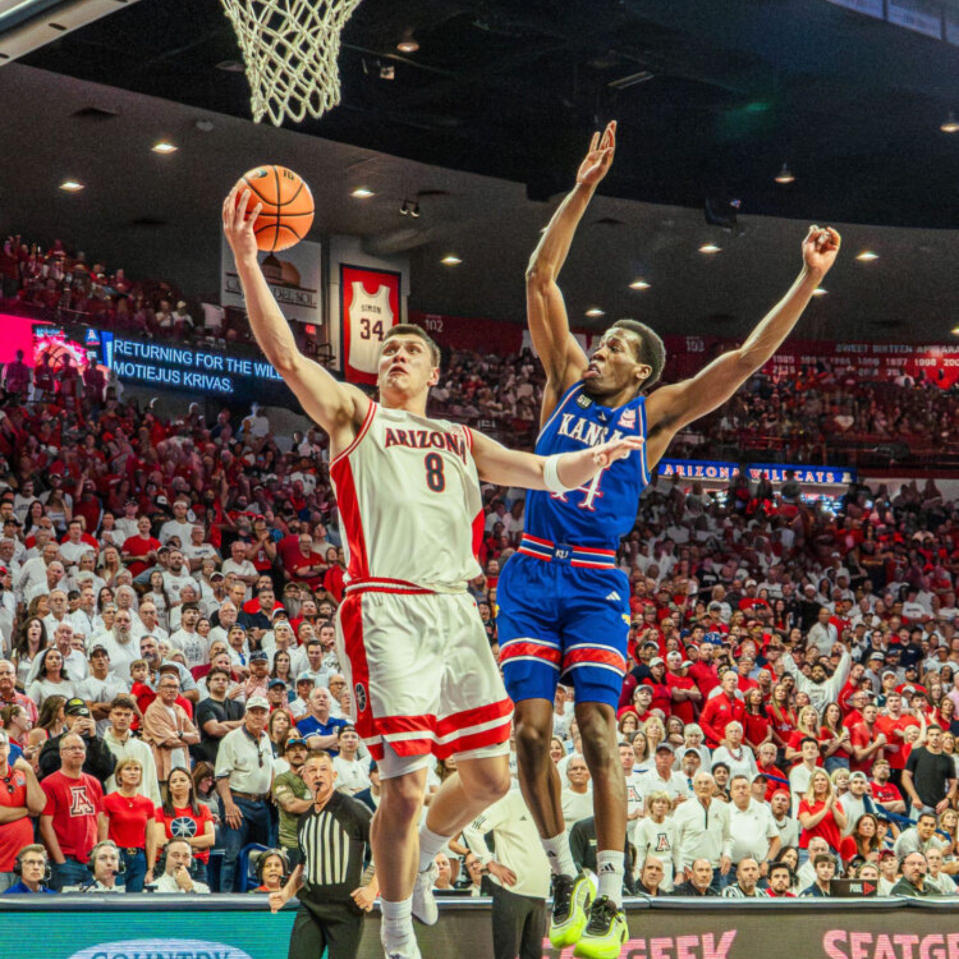 Arizona player attempts a layup against Kansas defender during a college basketball game
