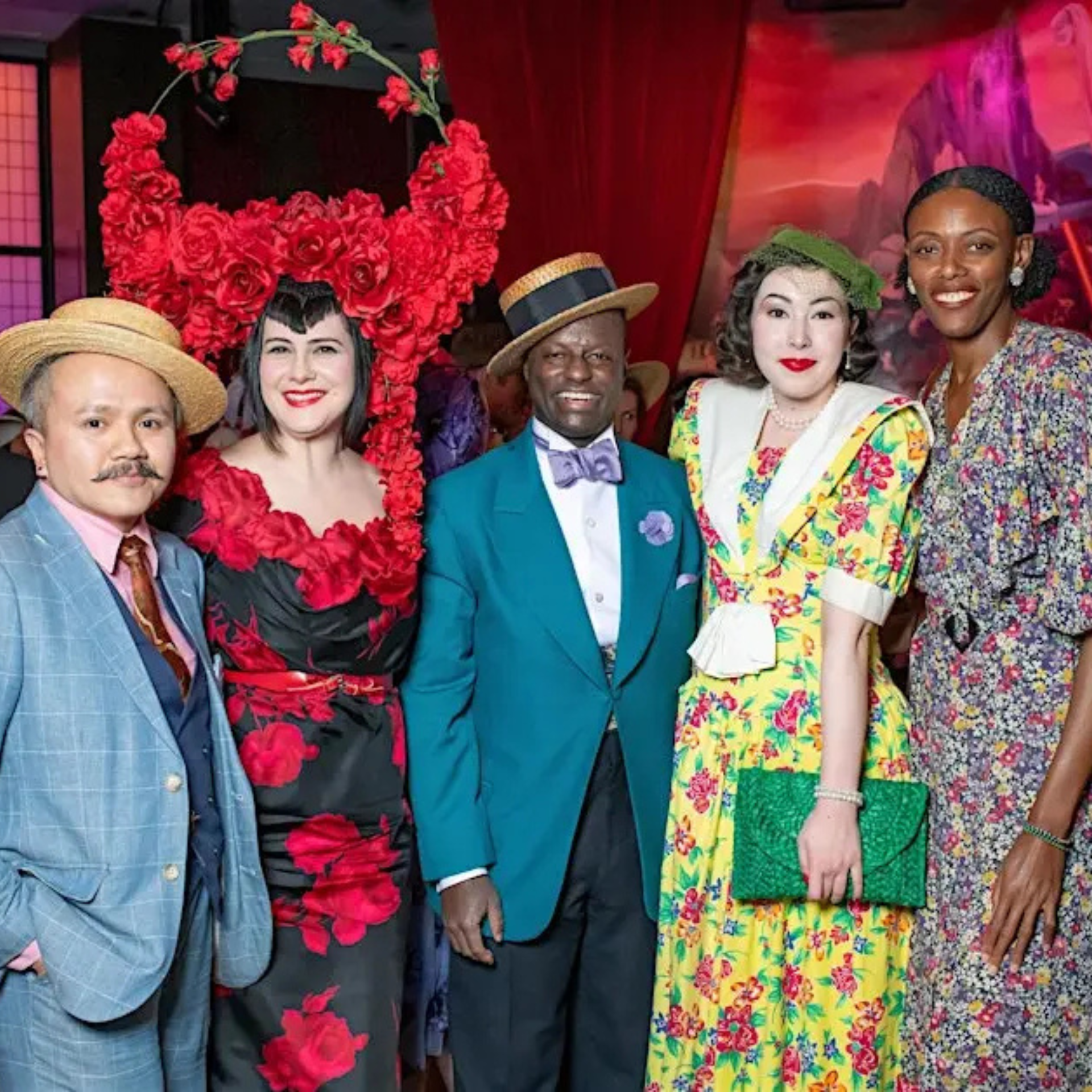 Group of five people in colorful vintage-inspired outfits posing at a festive event