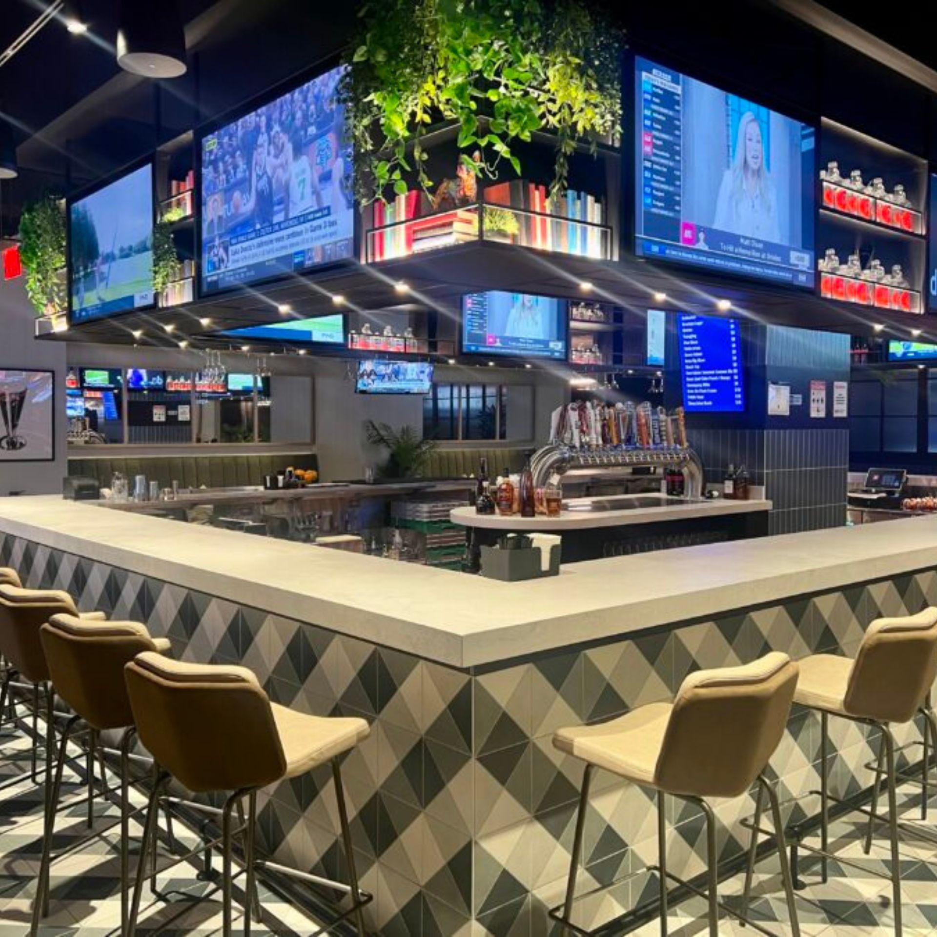 Modern sports bar with geometric counter, bar stools, and multiple TVs above the bar