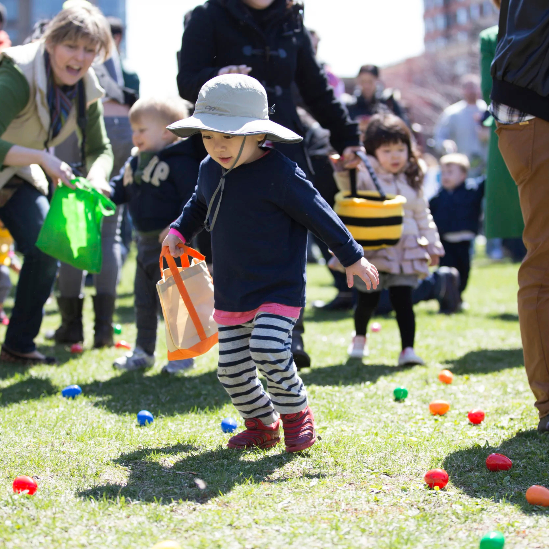 Children collecting colorful eggs during an outdoor Easter egg hunt in a sunny park