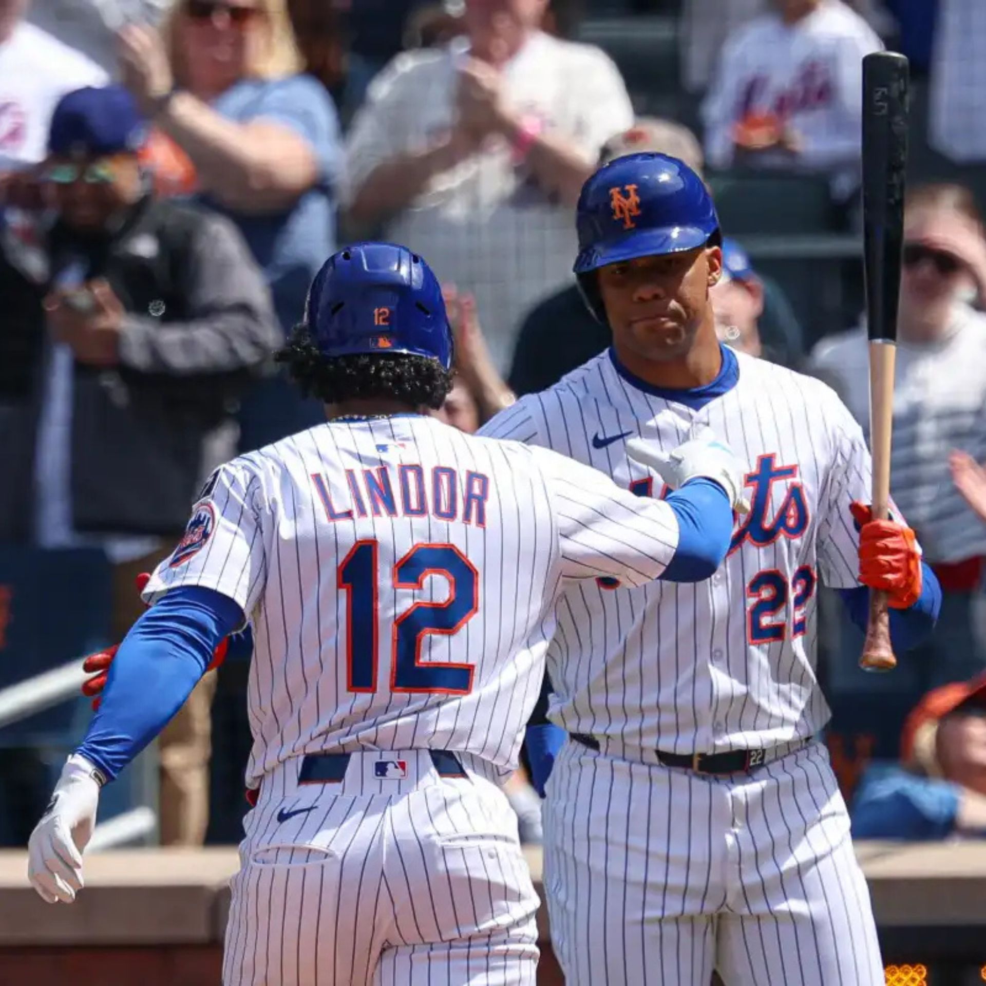 Two New York Mets players in pinstripe uniforms interact during a baseball game