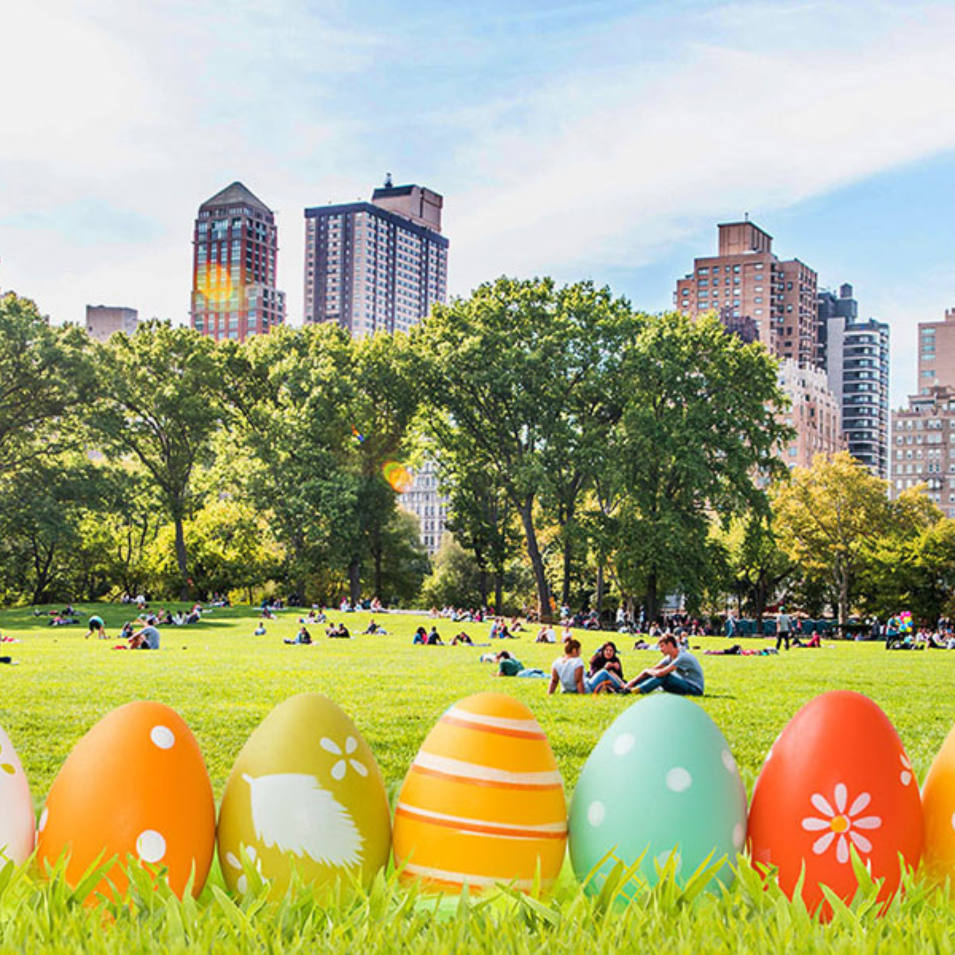 Colorful Easter eggs on grass in a city park with people relaxing and tall buildings in the background