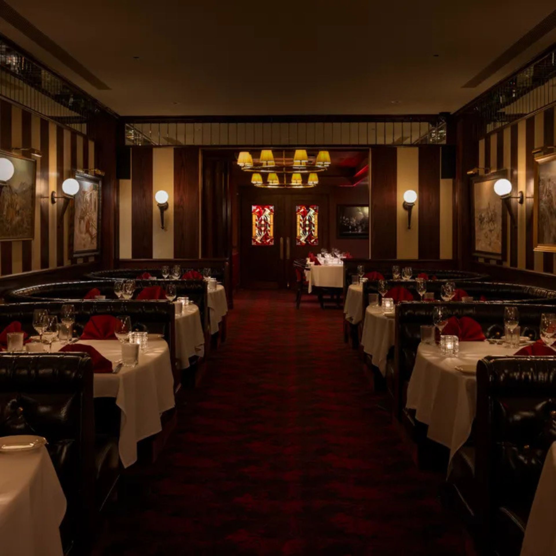Elegant restaurant dining room with leather booths, white tablecloths, and warm ambient lighting