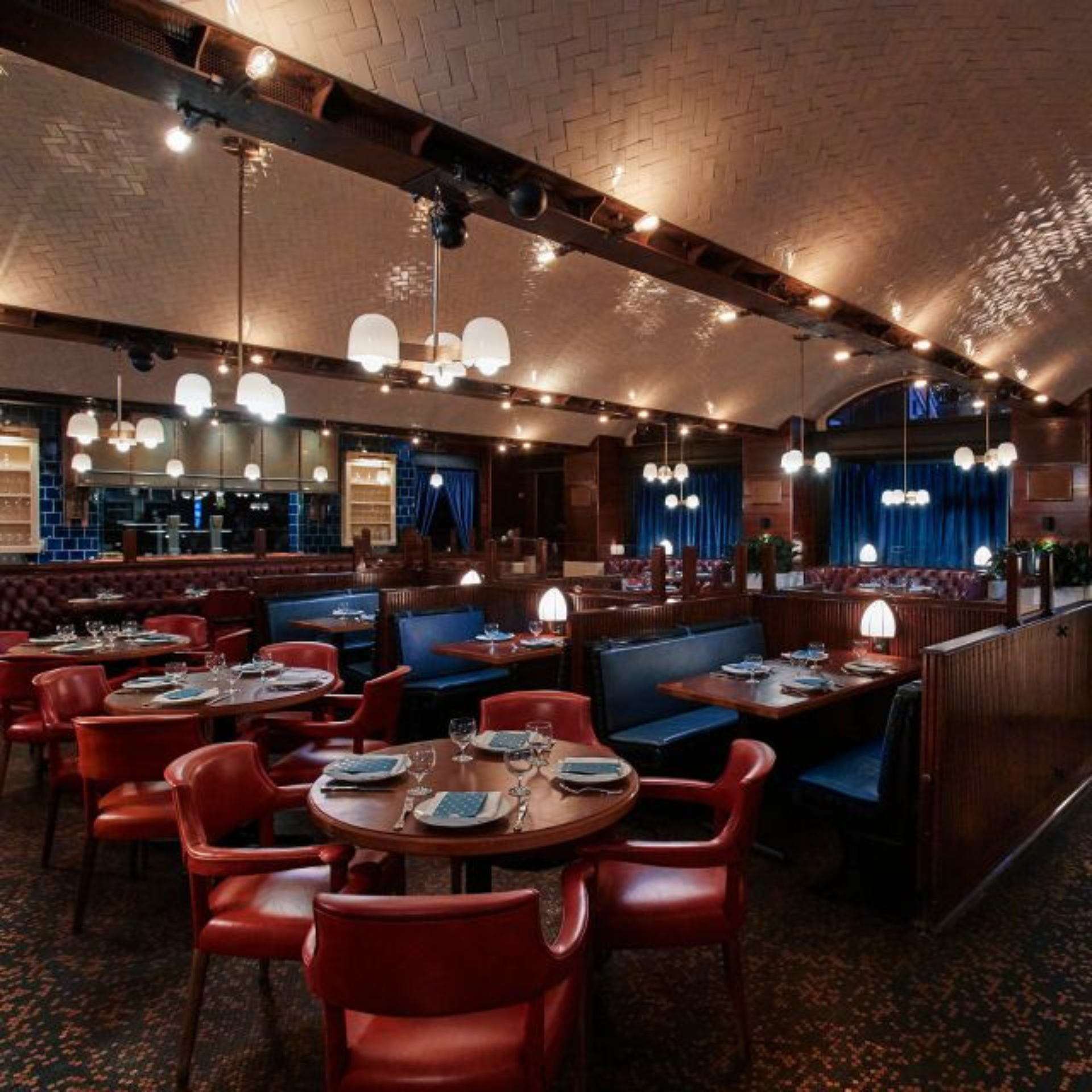 Upscale restaurant with red leather chairs, blue booths, and arched tiled ceiling