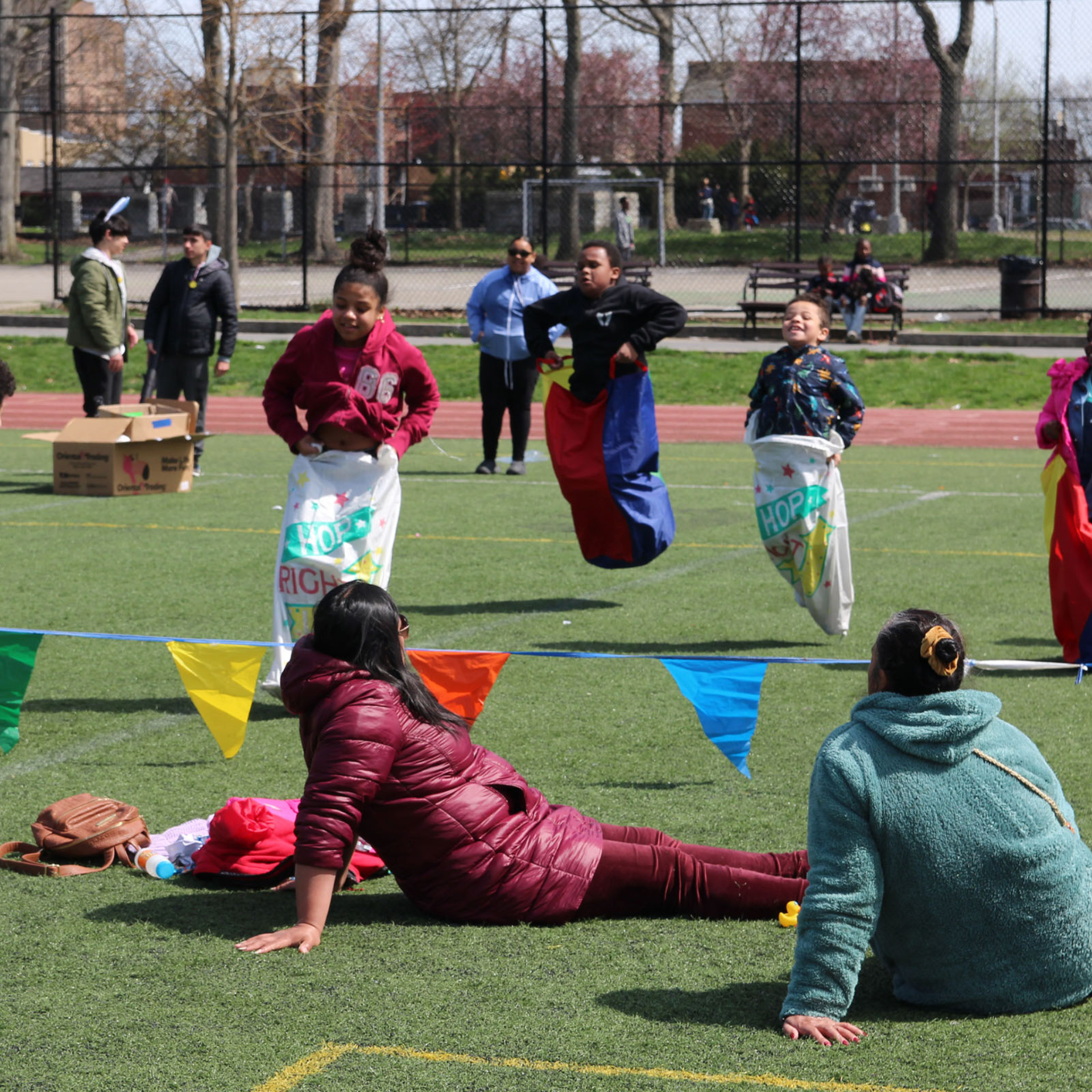 Children racing in colorful sacks on a sports field during a festive community event
