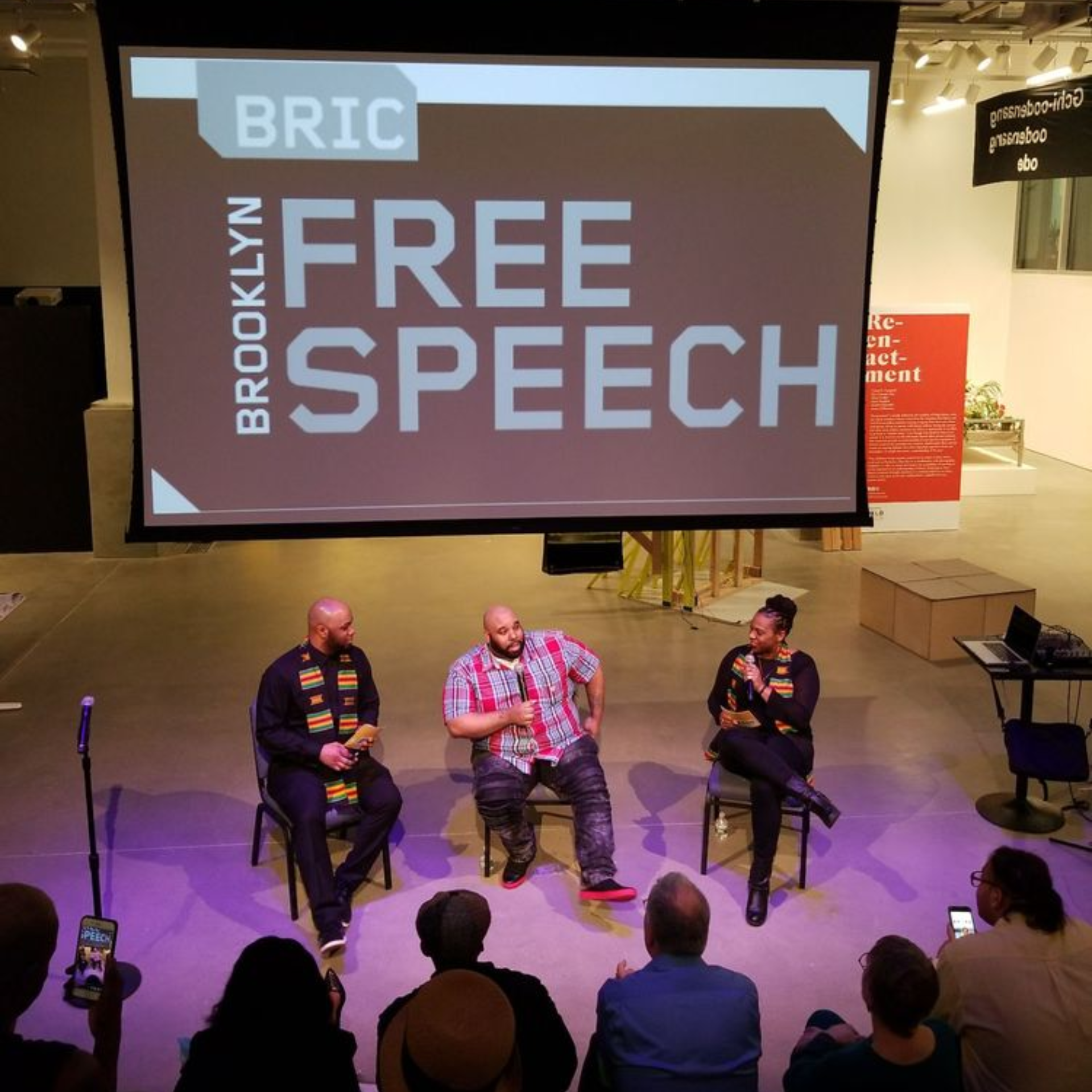 Panel discussion at BRIC Brooklyn with three speakers on stage under “Free Speech” projection screen