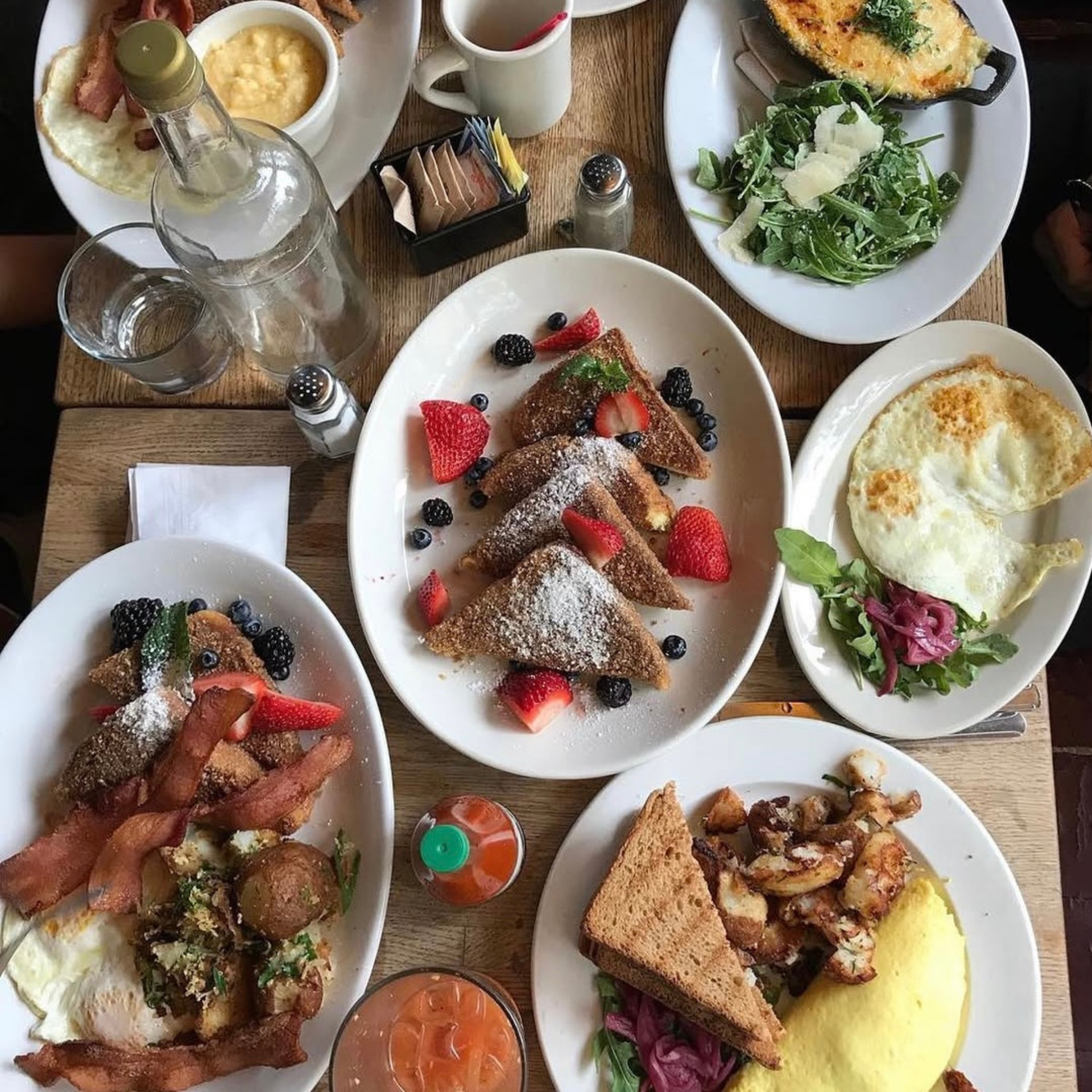 Table with French toast, eggs, bacon, potatoes, and assorted breakfast dishes