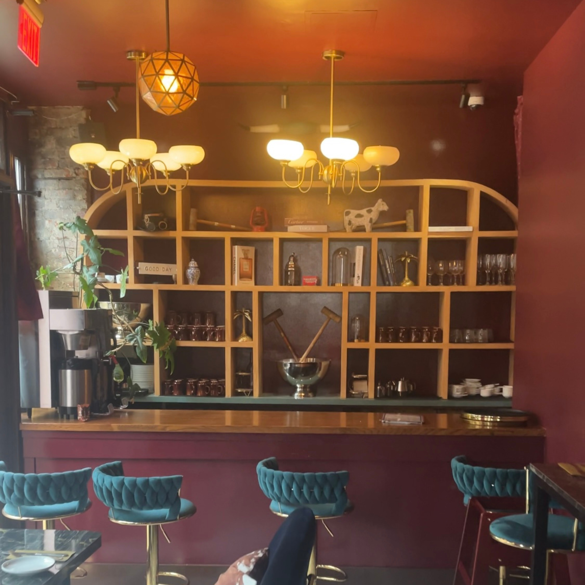 Stylish café bar with burgundy décor, teal stools, and decorative shelving