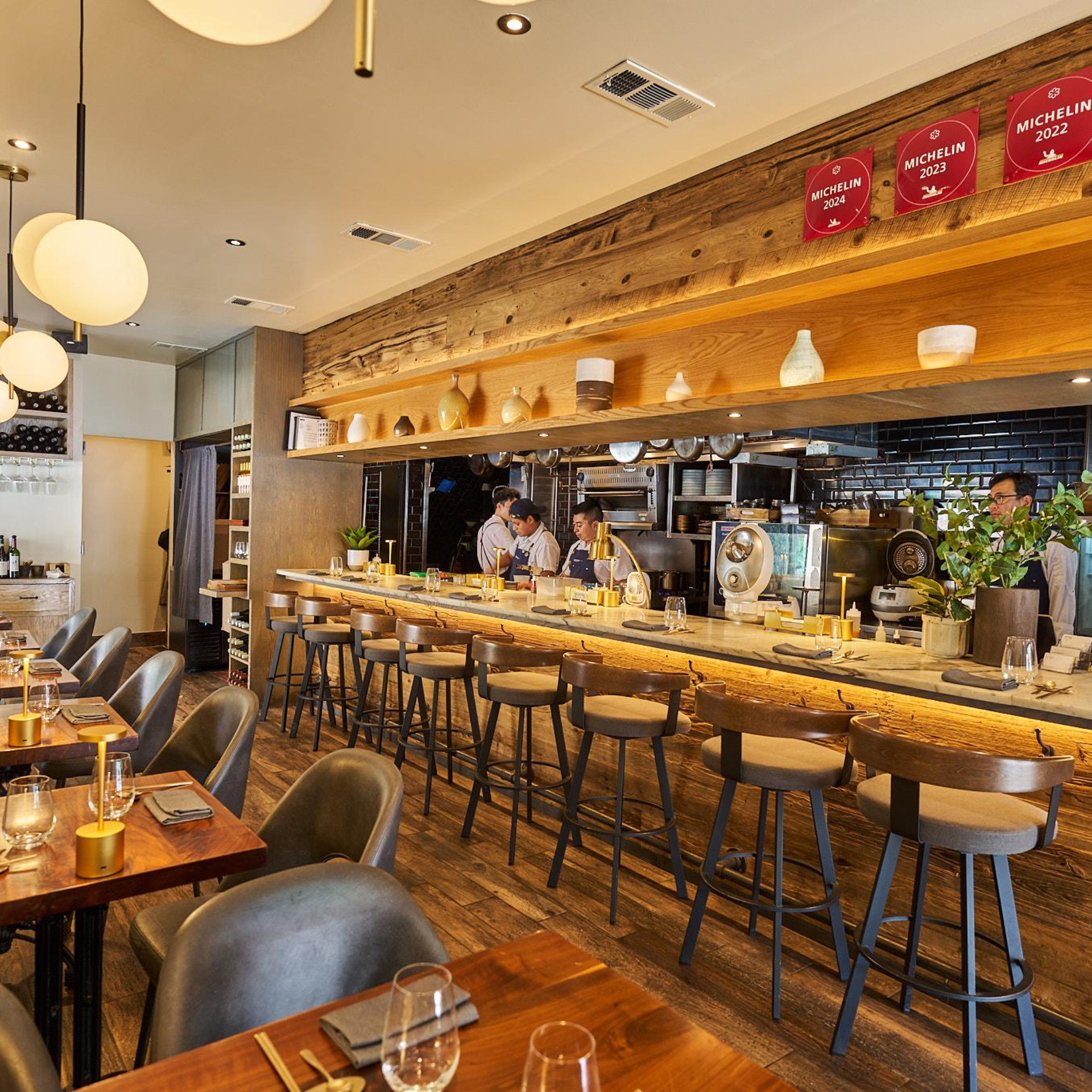 Modern restaurant with open kitchen, wooden bar, and Michelin award plaques