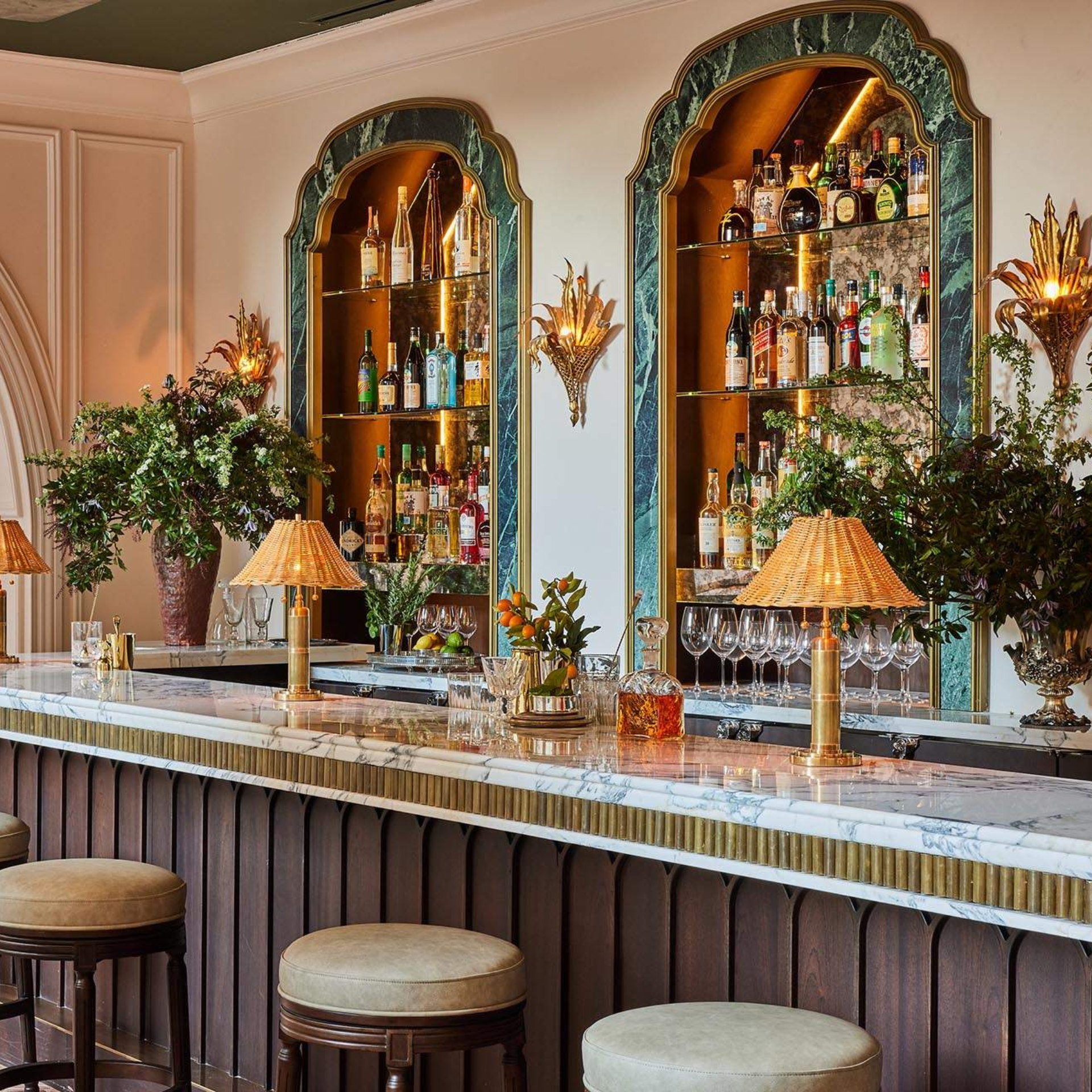Sophisticated bar with marble counter, arched shelves, and warm lighting