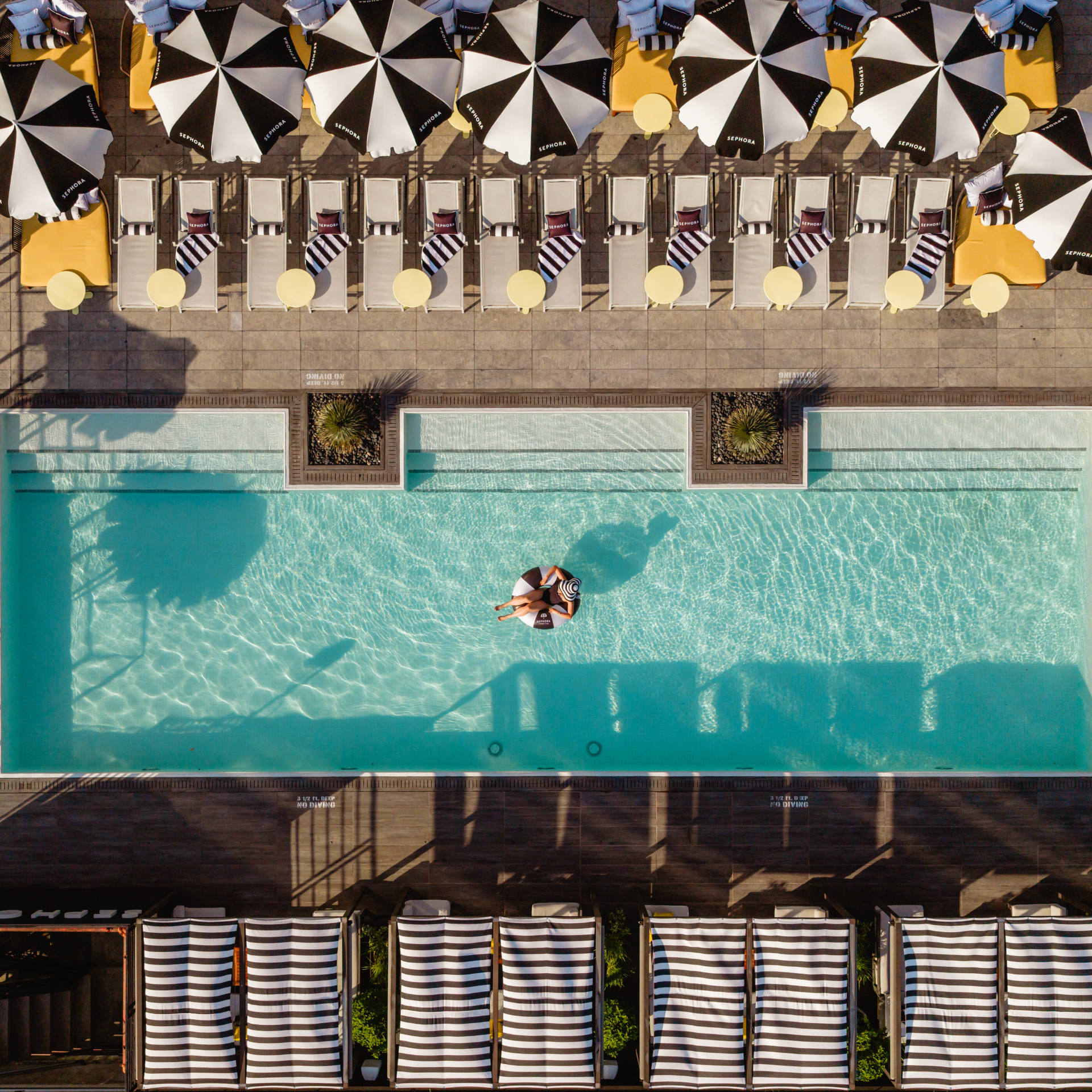 Aerial view of hotel swimming pool with lounge chairs and umbrellas, leisure spot for relaxation, sunbathing, and daily things to do in NYC any day