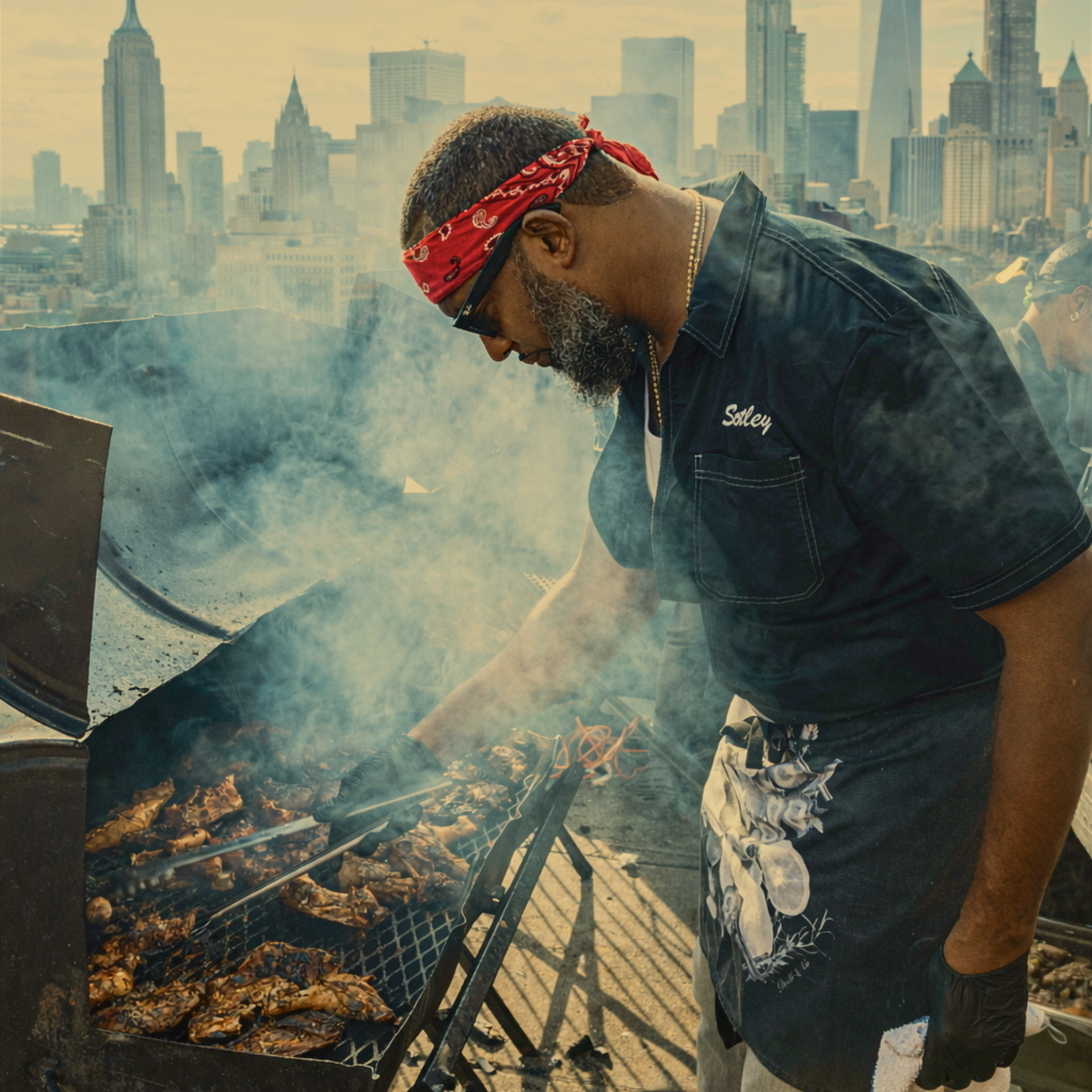 Person grilling meat on a smoky rooftop barbecue with New York City skyline in the background
