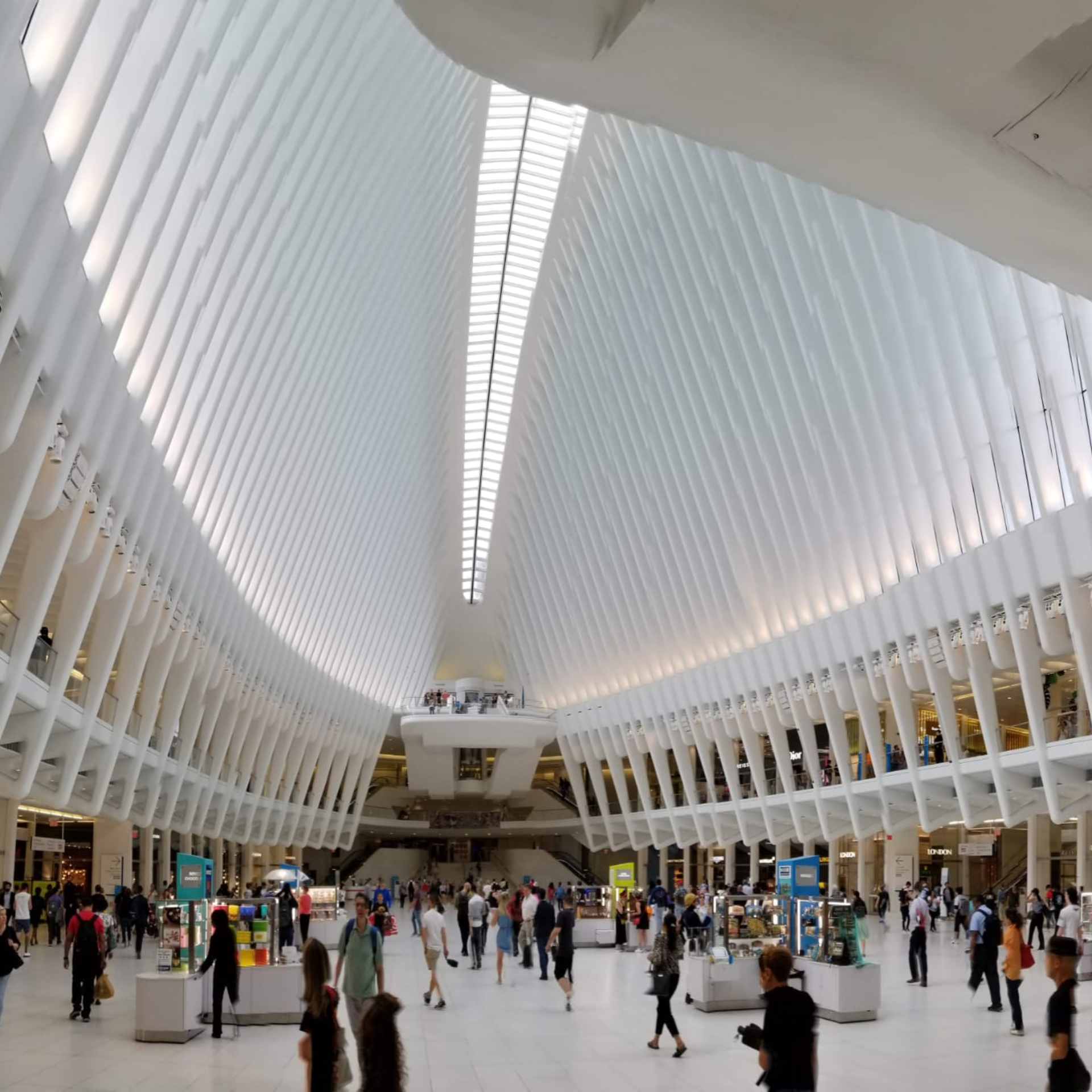 Futuristic public space with vaulted rib‑beam ceiling, central skylight, bright concourse, kiosks, and crowds walking through expansive modern architecture