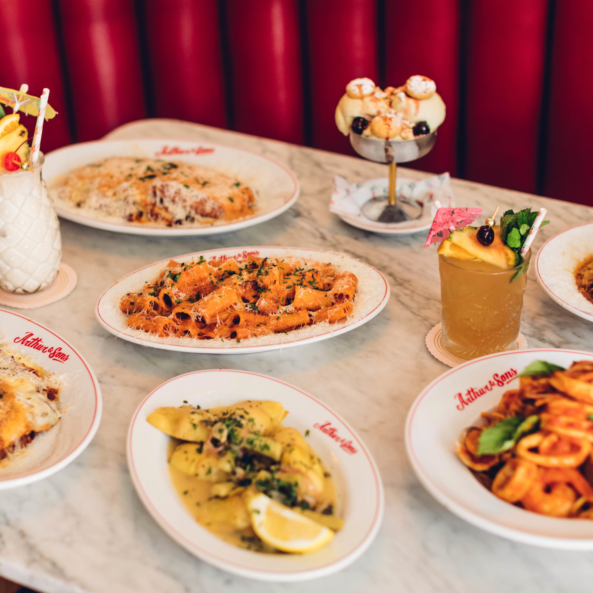 Arthur & Sons NYC restaurant table with pasta dishes, ravioli, cocktails, and cream puff dessert, Italian dining experience featured in daily things to do in NYC any day