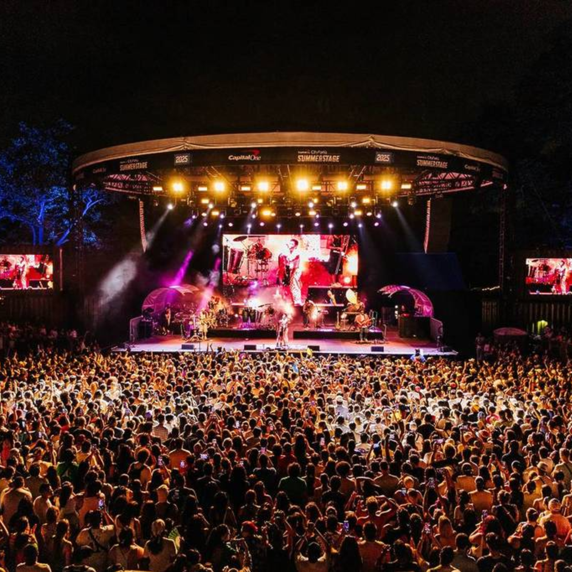NYC SummerStage outdoor concert with Capital One City Parks Foundation banner, band performing under colorful lights for packed crowd, live music event featured in daily things to do in NYC any day
