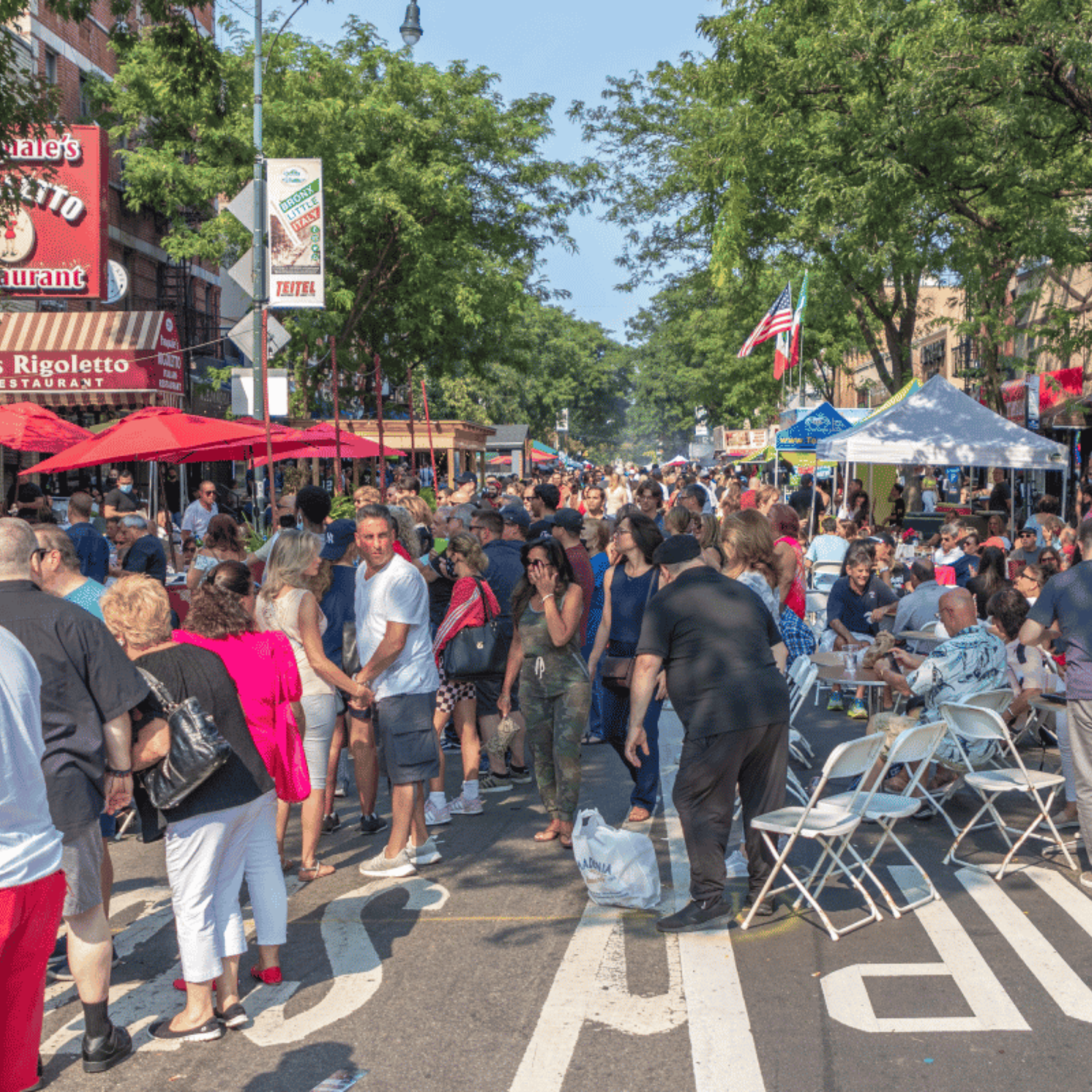 NYC street festival with crowds walking and dining at tables under red umbrellas and food stalls, lively urban community gathering featured in daily things to do in NYC any day