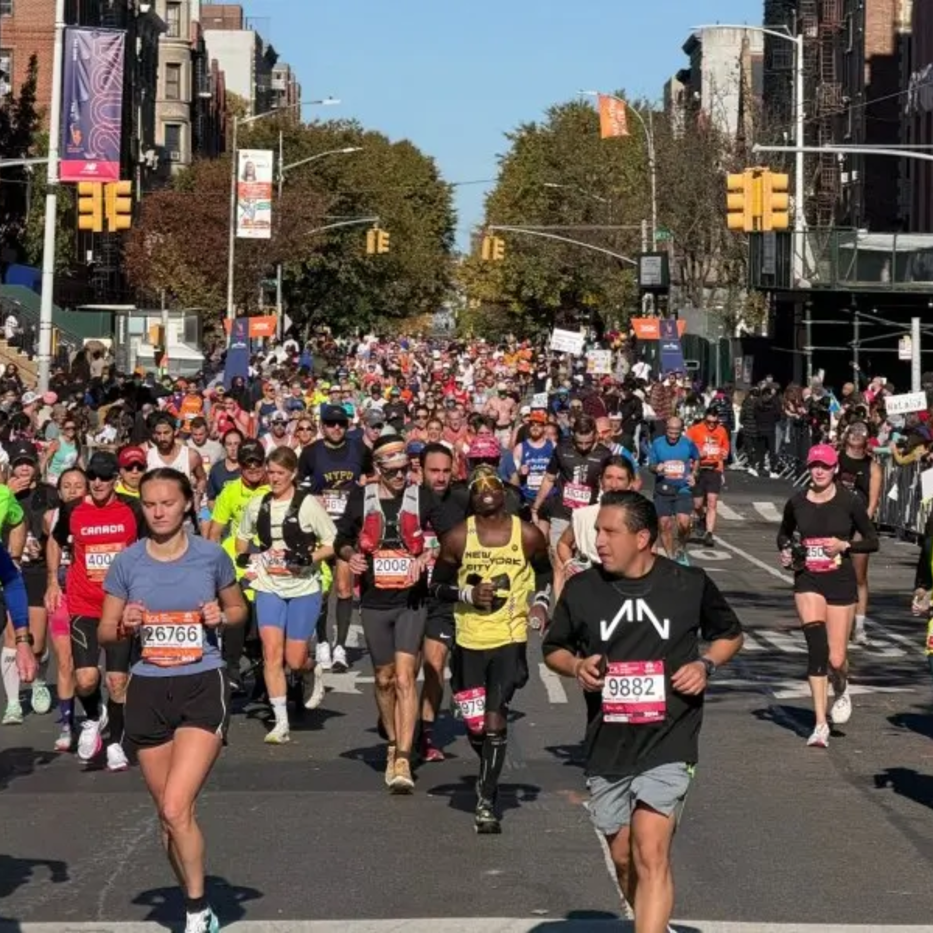 NYC marathon with runners in numbered bibs racing through city streets lined with spectators, energetic urban event featured in daily things to do in NYC any day