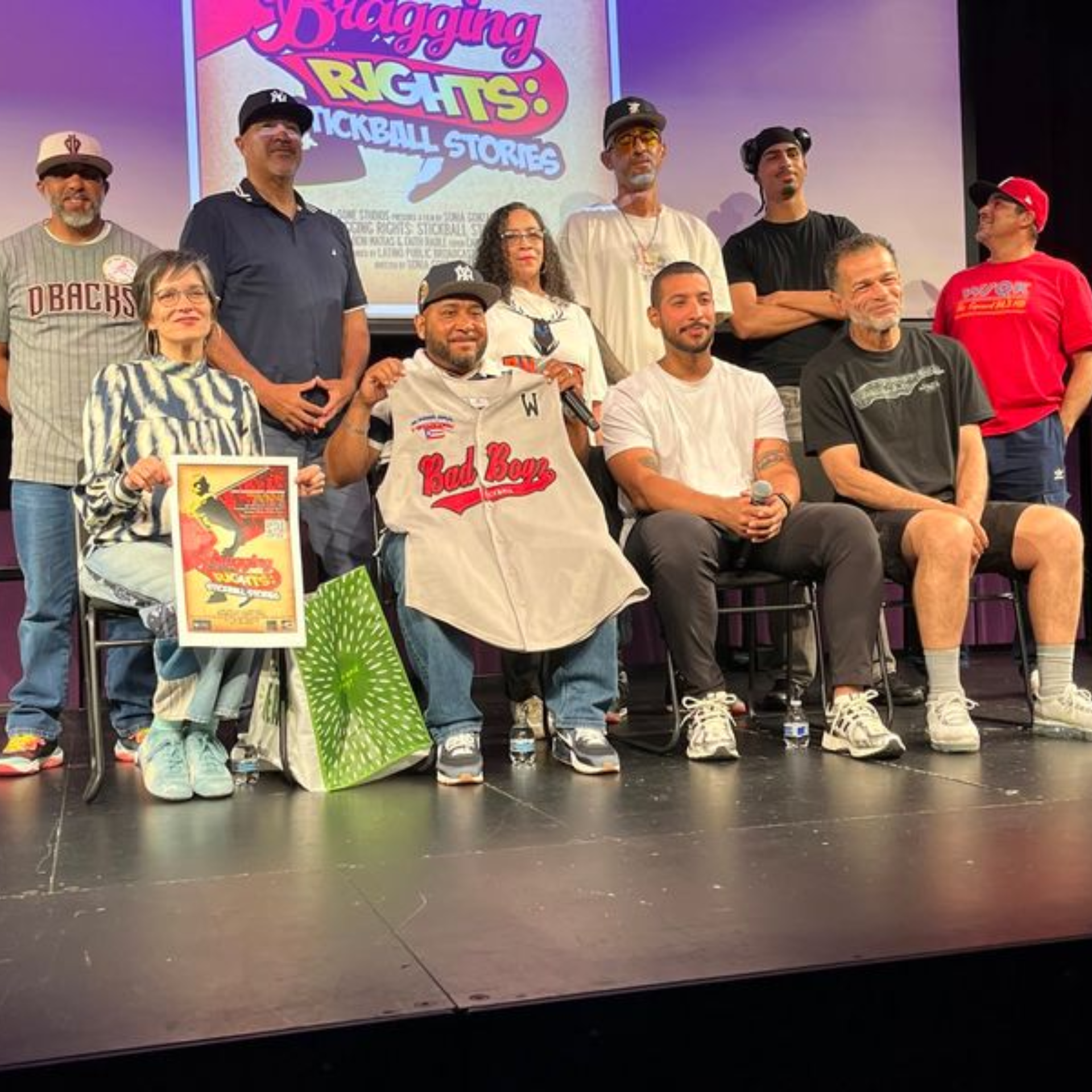 Group on stage at NYC Bragging Rights Kickball Stories event holding jersey and poster, community sports presentation featured in daily things to do in NYC any day