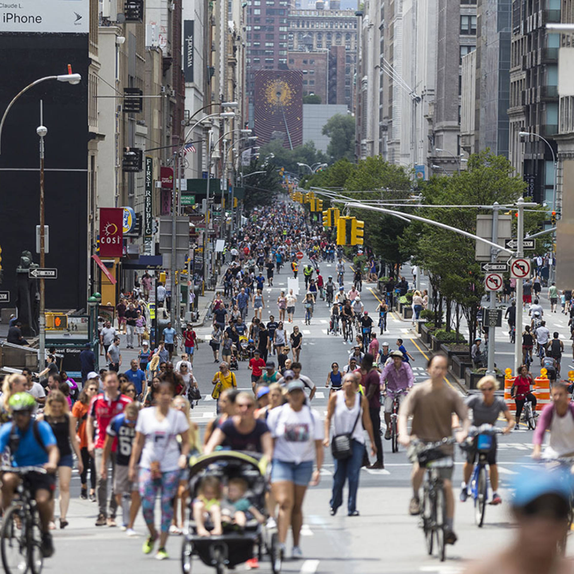NYC city street closed to cars with large crowd walking, cycling, and strollers among tall buildings, vibrant urban community event featured in daily things to do in NYC any day