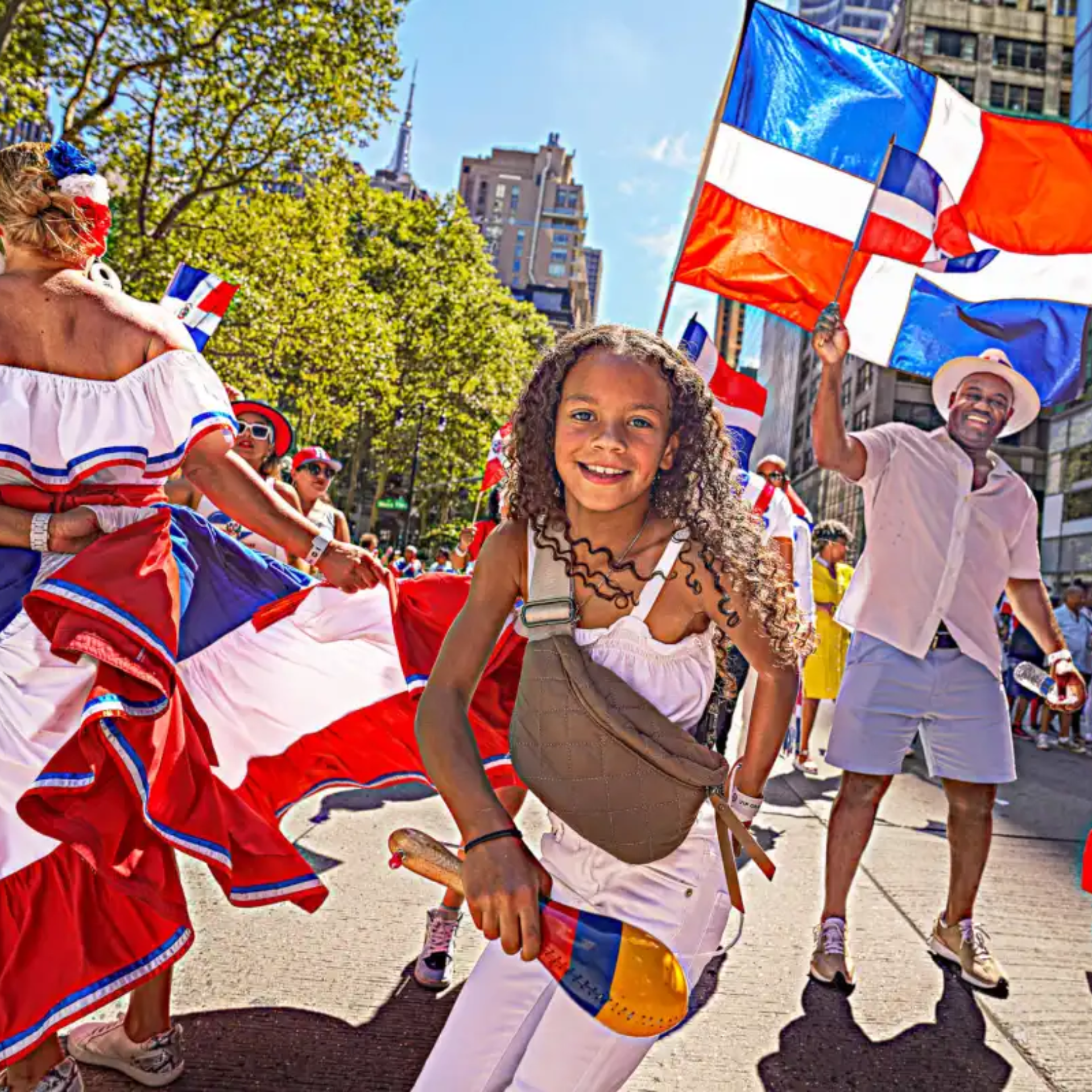Child with colorful maraca smiling at NYC Dominican parade with dancers waving flags and festive outfits, cultural street celebration featured in daily things to do in NYC any day