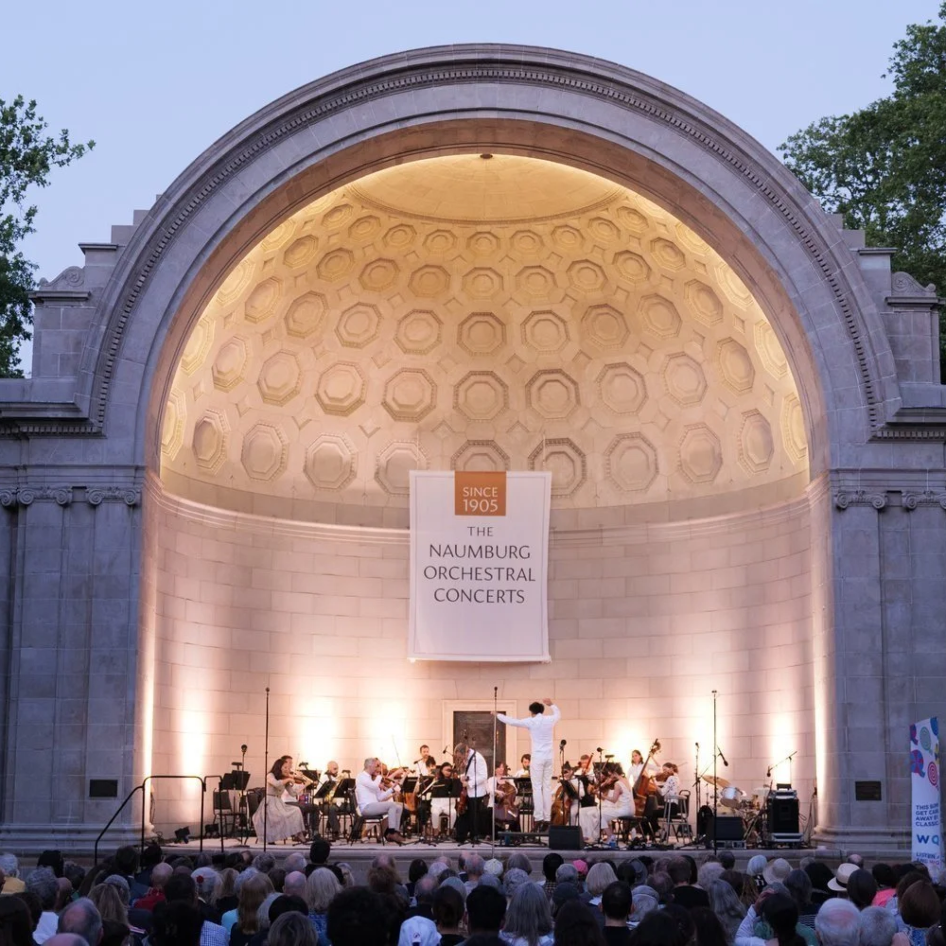 Central Park Naumburg Bandshell orchestral concert with musicians performing under historic dome, outdoor classical music tradition featured in daily things to do in NYC any day