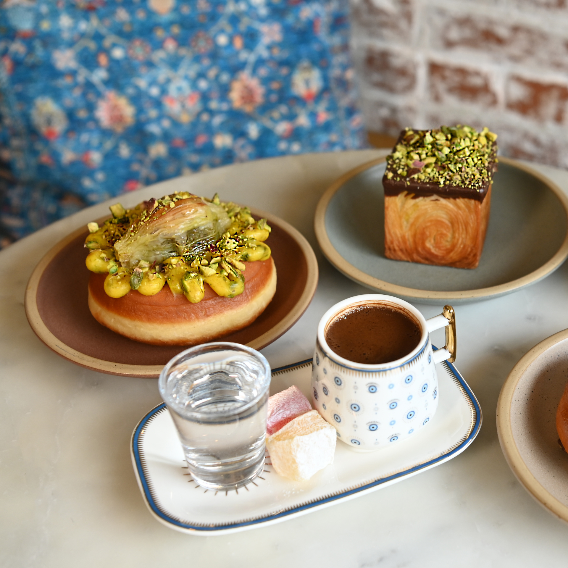 NYC table with Turkish coffee, water, delights, pistachio pastries, and baklava, Middle Eastern dessert culture featured in daily things to do in NYC any day