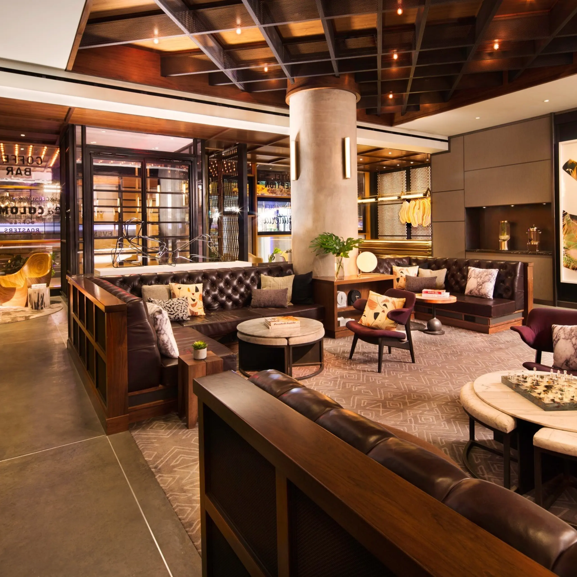 Upscale NYC lounge with leather sofas, patterned chairs, warm lighting, and bar backdrop, stylish social space featured in daily things to do in NYC any day