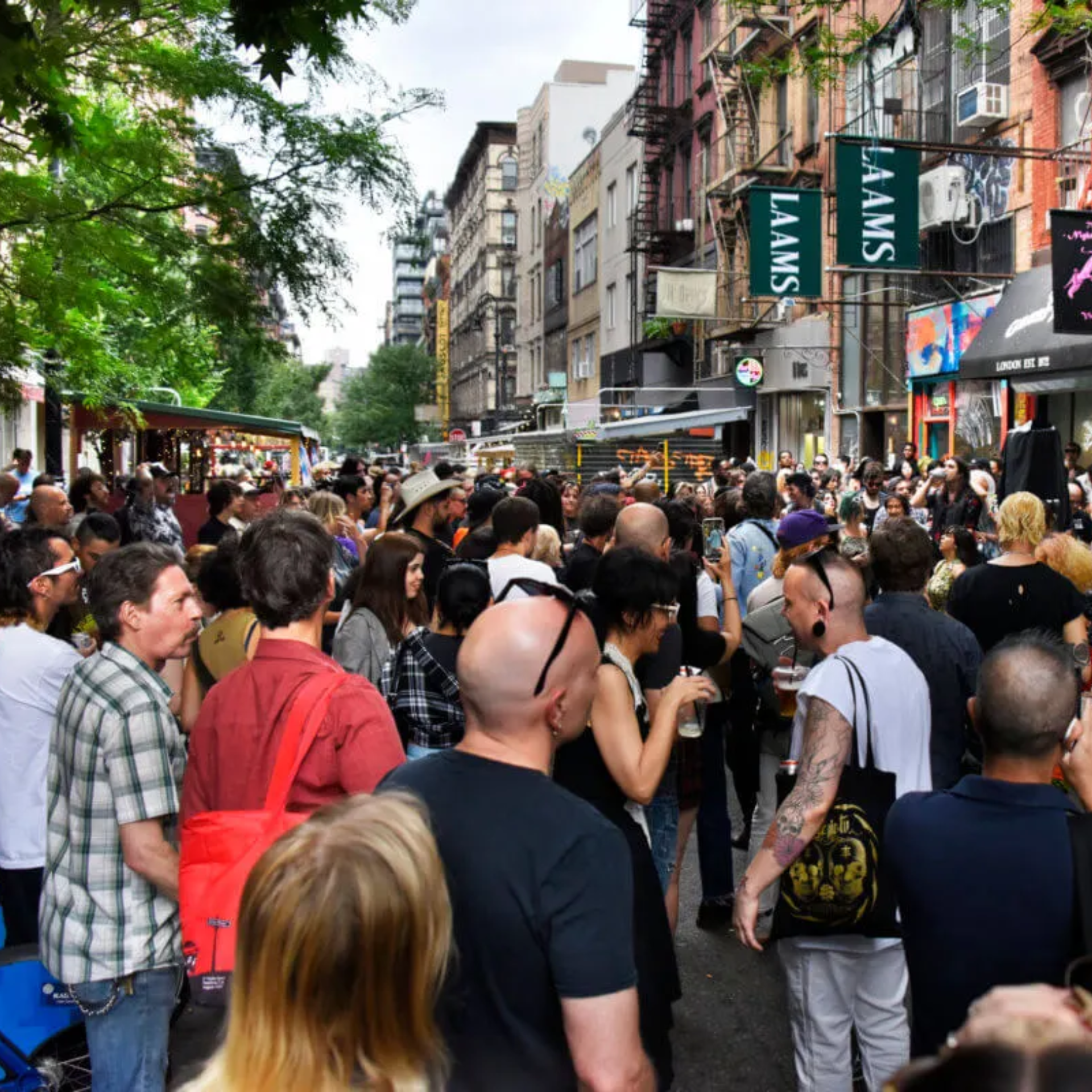 NYC street festival crowd gathered under LAAMS banners with people socializing, taking photos, and enjoying urban culture featured in daily things to do in NYC any day