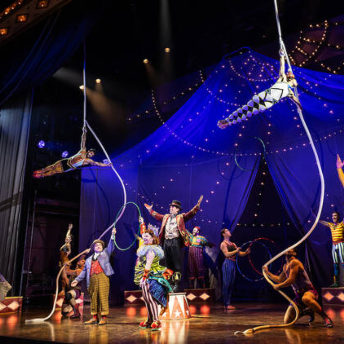 Colorful NYC circus performance with aerial acrobats, jugglers, and ringmaster on festive stage, Labor Day entertainment featured in daily things to do in NYC any day