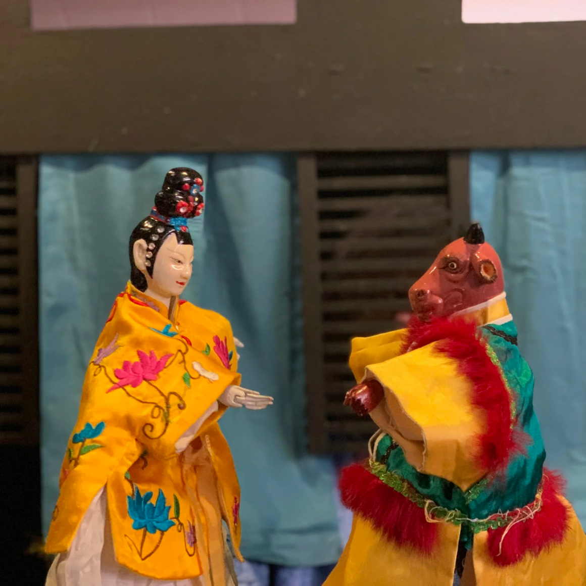NYC Labor Day puppetry performance with ornate human‑like puppet in yellow floral robe and animal‑like puppet in green robe on stage, cultural art featured in daily things to do in NYC any day