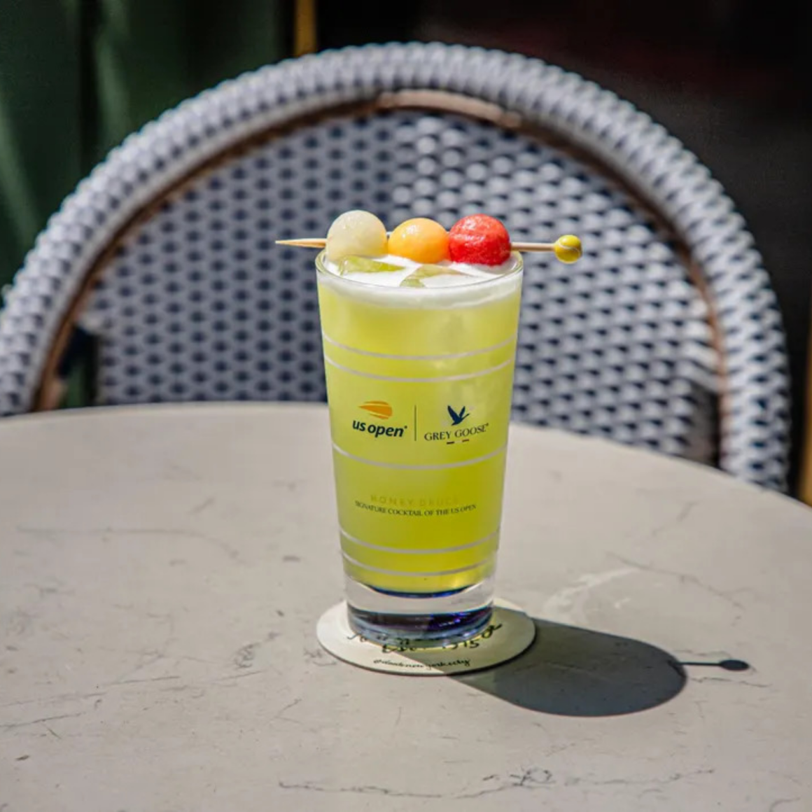 NYC Labor Day US Open Grey Goose cocktail with melon ball garnish on table, signature tennis drink featured in daily things to do in NYC any day