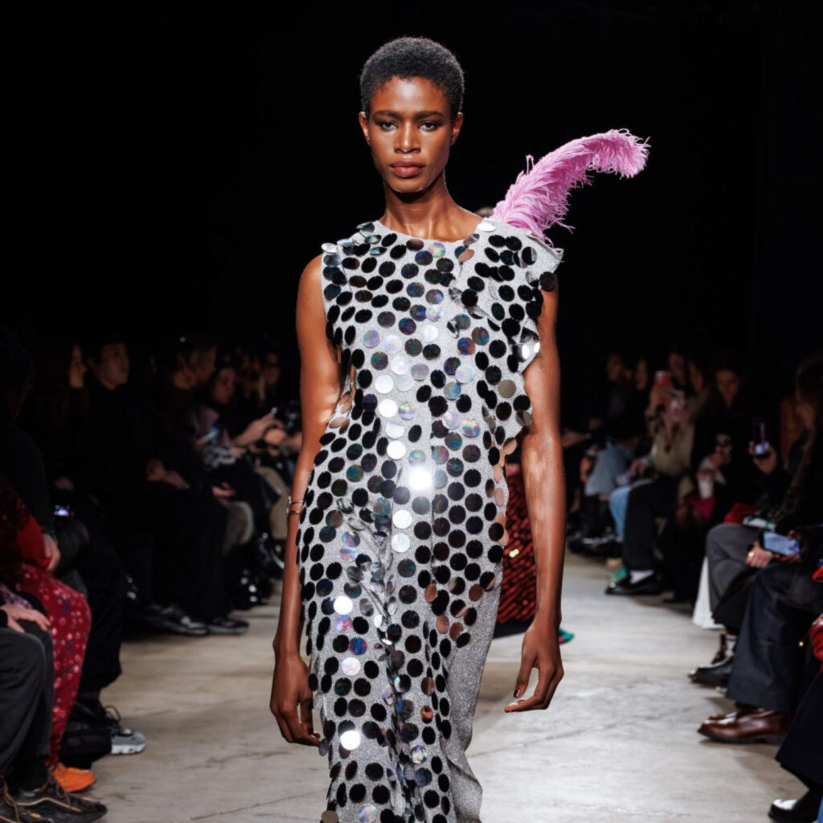 Runway fashion model in shimmering avant‑garde sequin dress with pink feather detail at NYC Labor Day fashion show, high‑style event featured in daily things to do in NYC any day