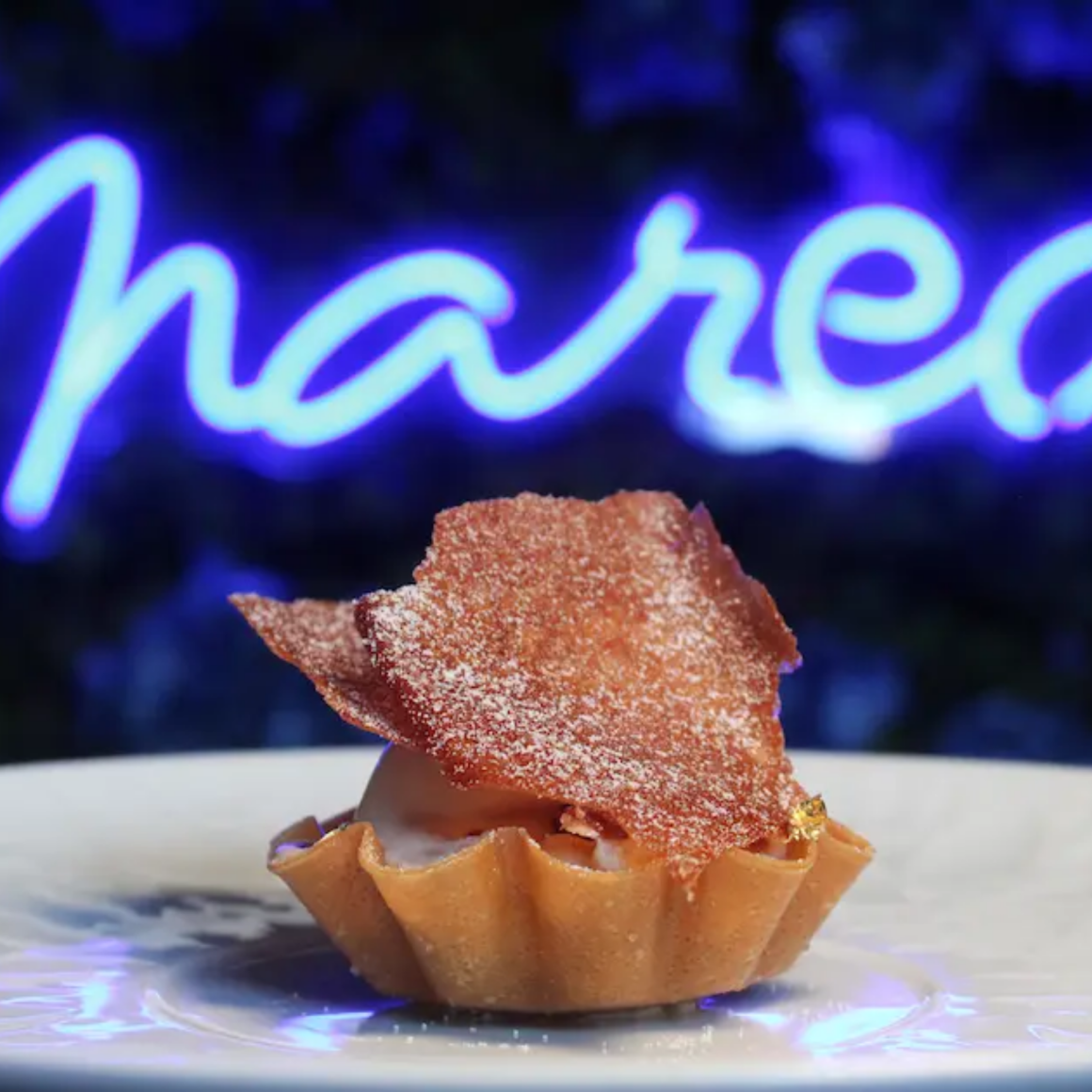 NYC Labor Day plated dessert at Marea with tart shell, creamy filling, caramelized crisp topping, and neon sign glow, culinary experience featured in daily things to do in NYC any day
