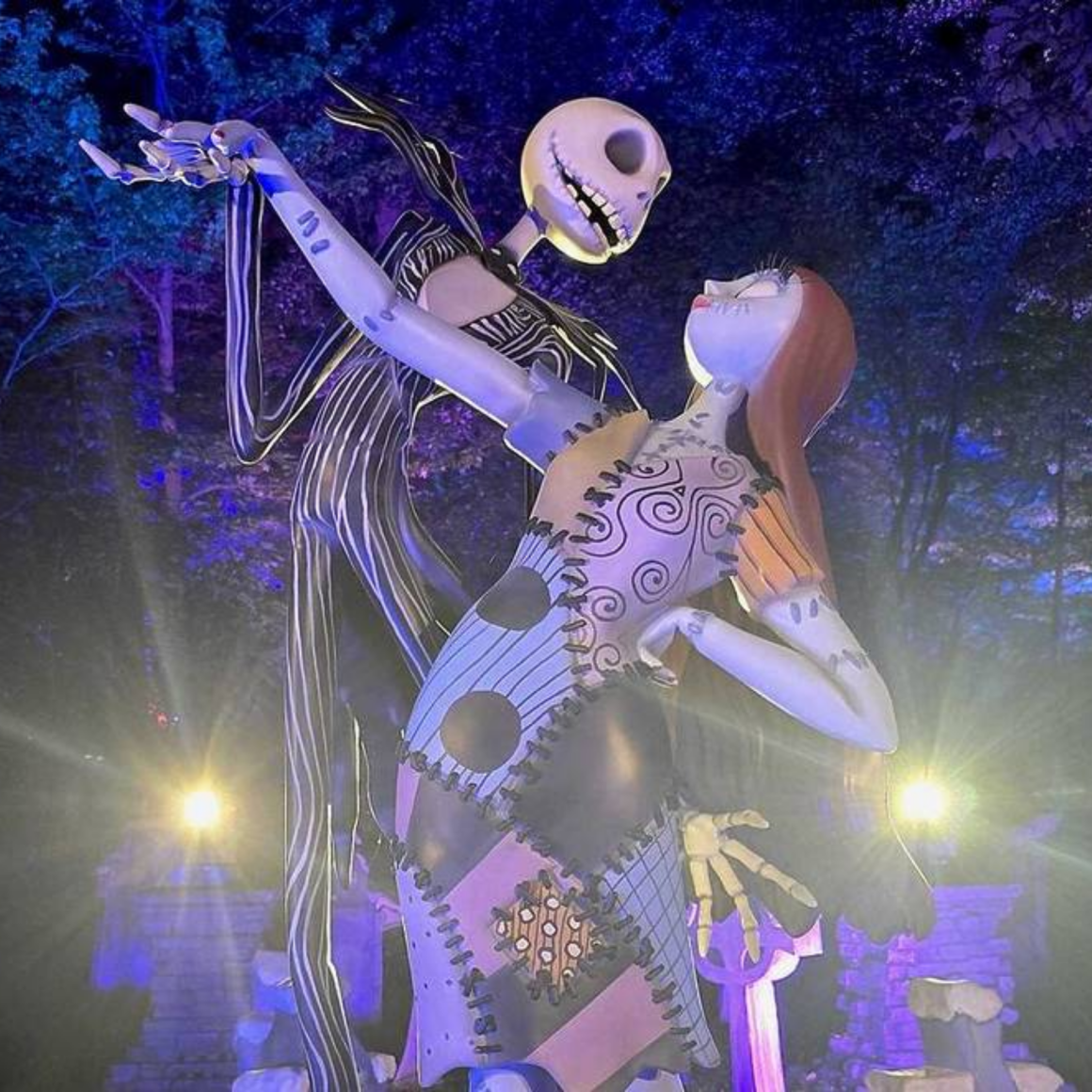 NYC Labor Day display with Jack Skellington and Sally statues posed dancing under purple and blue lights, holiday cultural installation featured in daily things to do in NYC any day