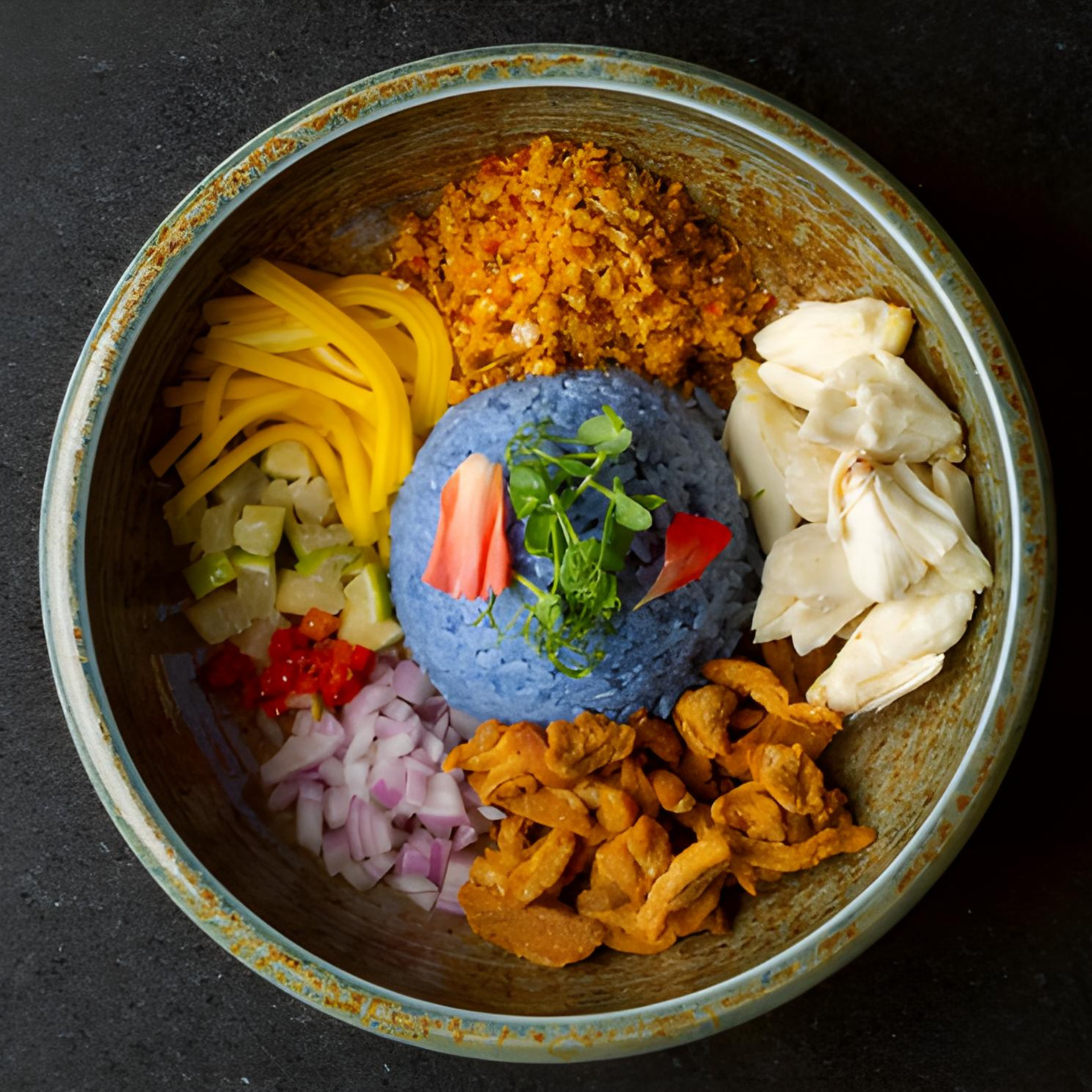 Blue rice dish with herbs, petals, and assorted sides