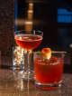 Three colorful cocktails with garnishes on dark bar counter