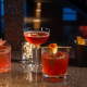 Three colorful cocktails with garnishes on dark bar counter